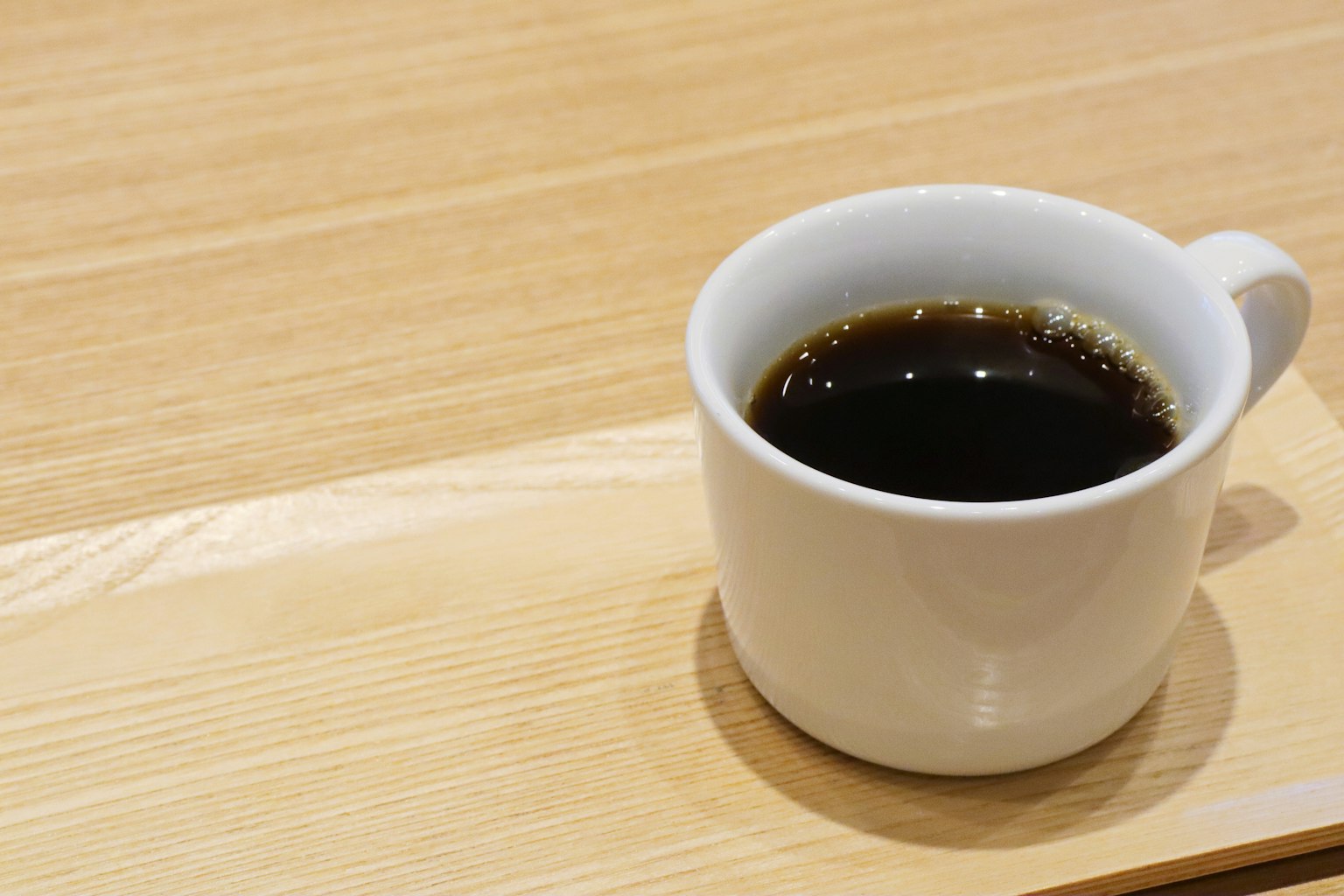 白色咖啡杯裝滿黑咖啡放在木桌上