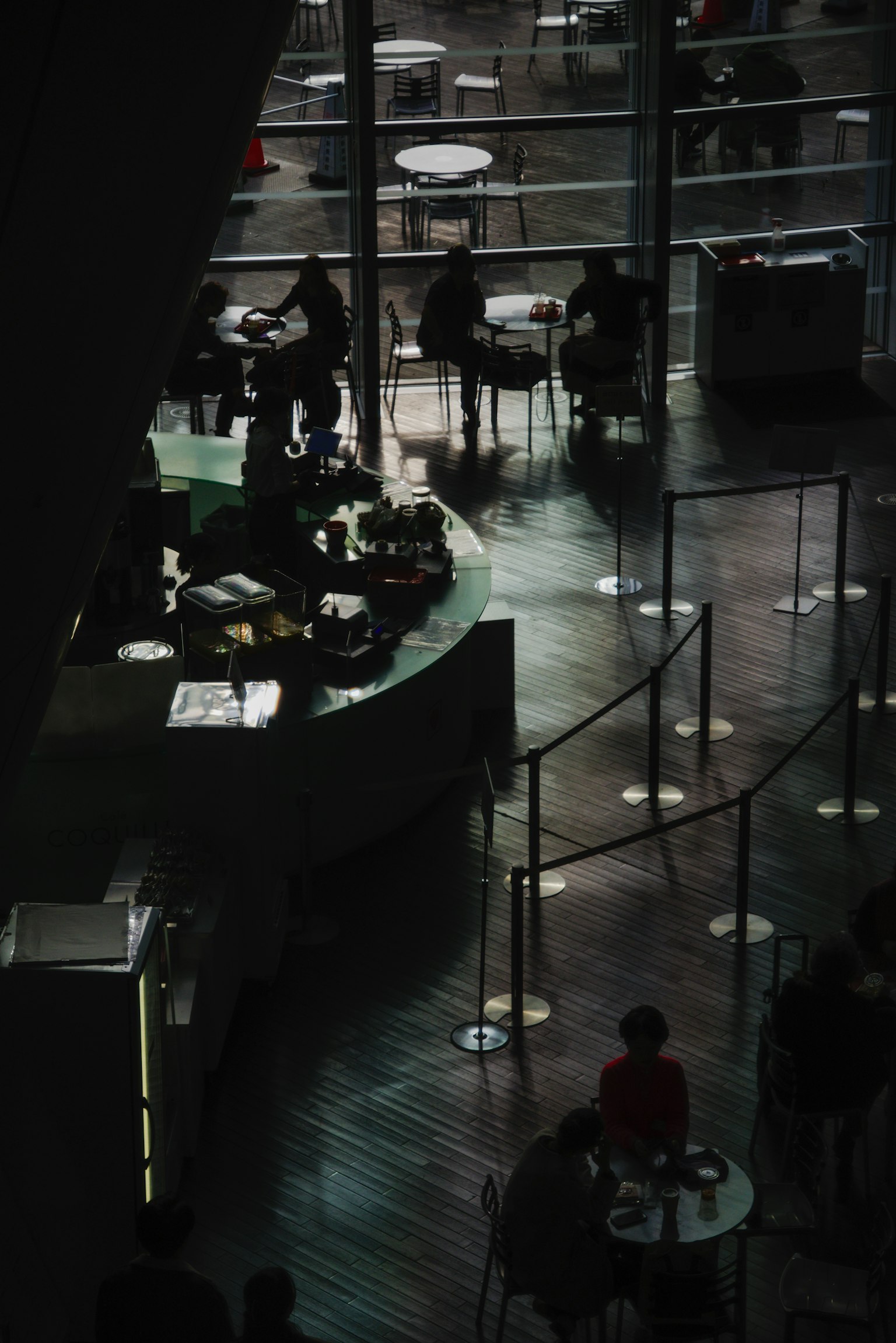 Interior of a dark café with people sitting at tables and reflections of light
