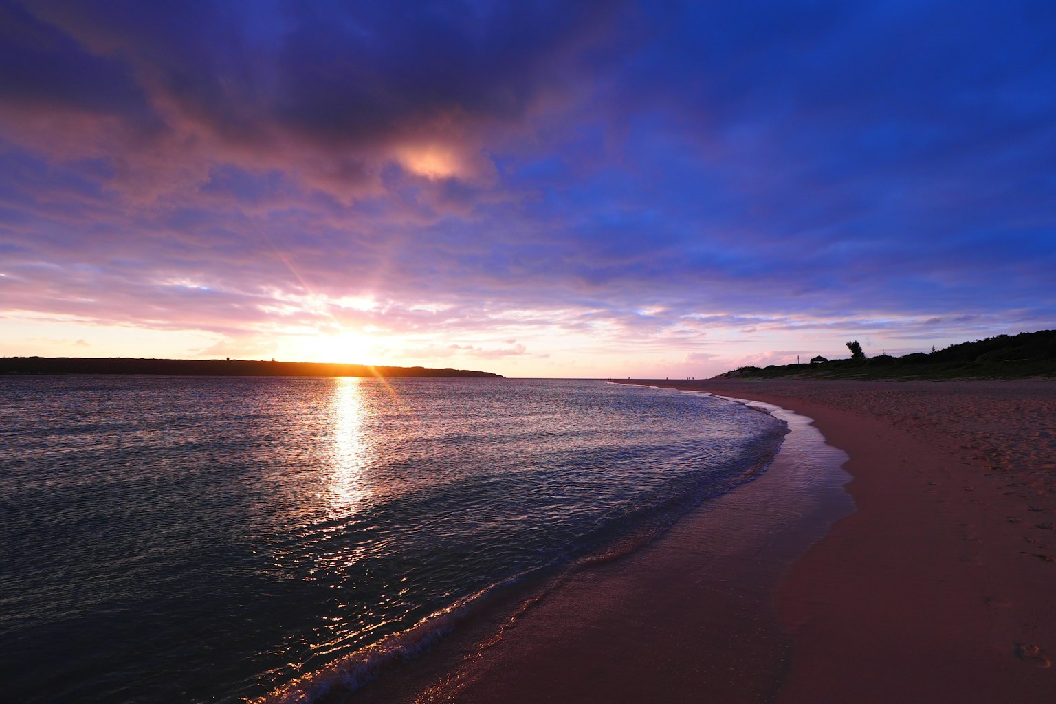 Bellissimo tramonto su una spiaggia tranquilla con onde leggere
