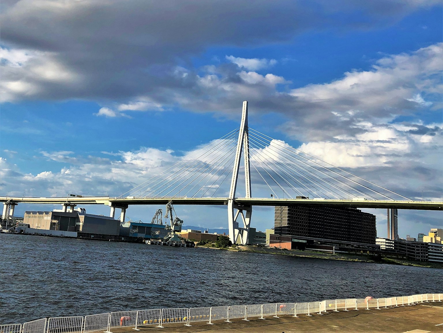 สะพานขนาดใหญ่ข้ามแม่น้ำใต้ท้องฟ้าสีฟ้าพร้อมเมฆ