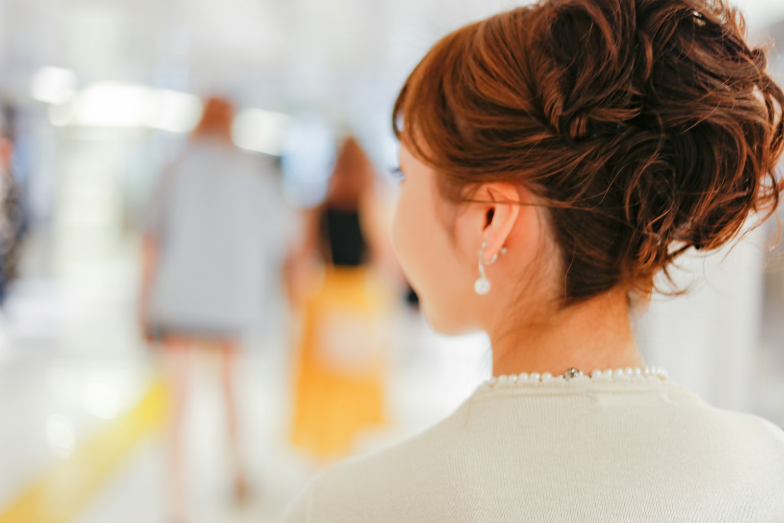 Vue de dos d'une femme avec des cheveux coiffés et des boucles d'oreilles arrière flou