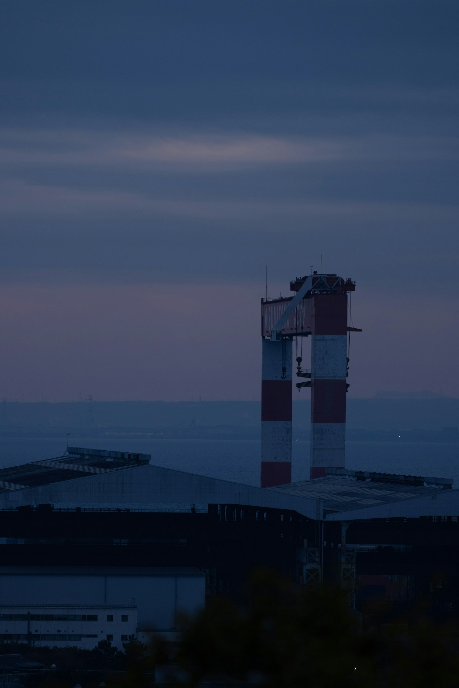 Silhouette di un camino di fabbrica e di un edificio al crepuscolo