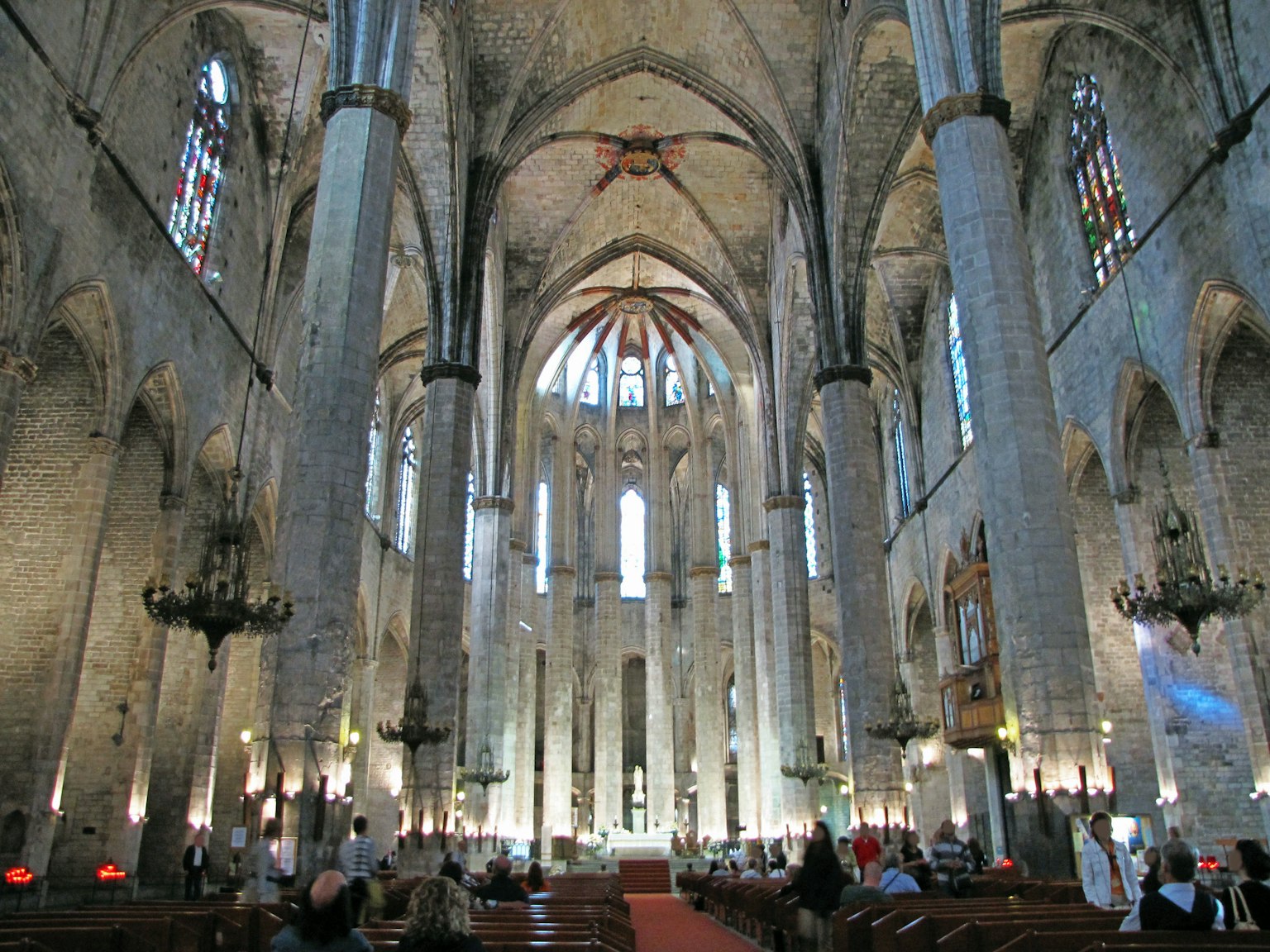 Innenraum einer großen Kathedrale mit hohen Bögen und farbigen Fenstern