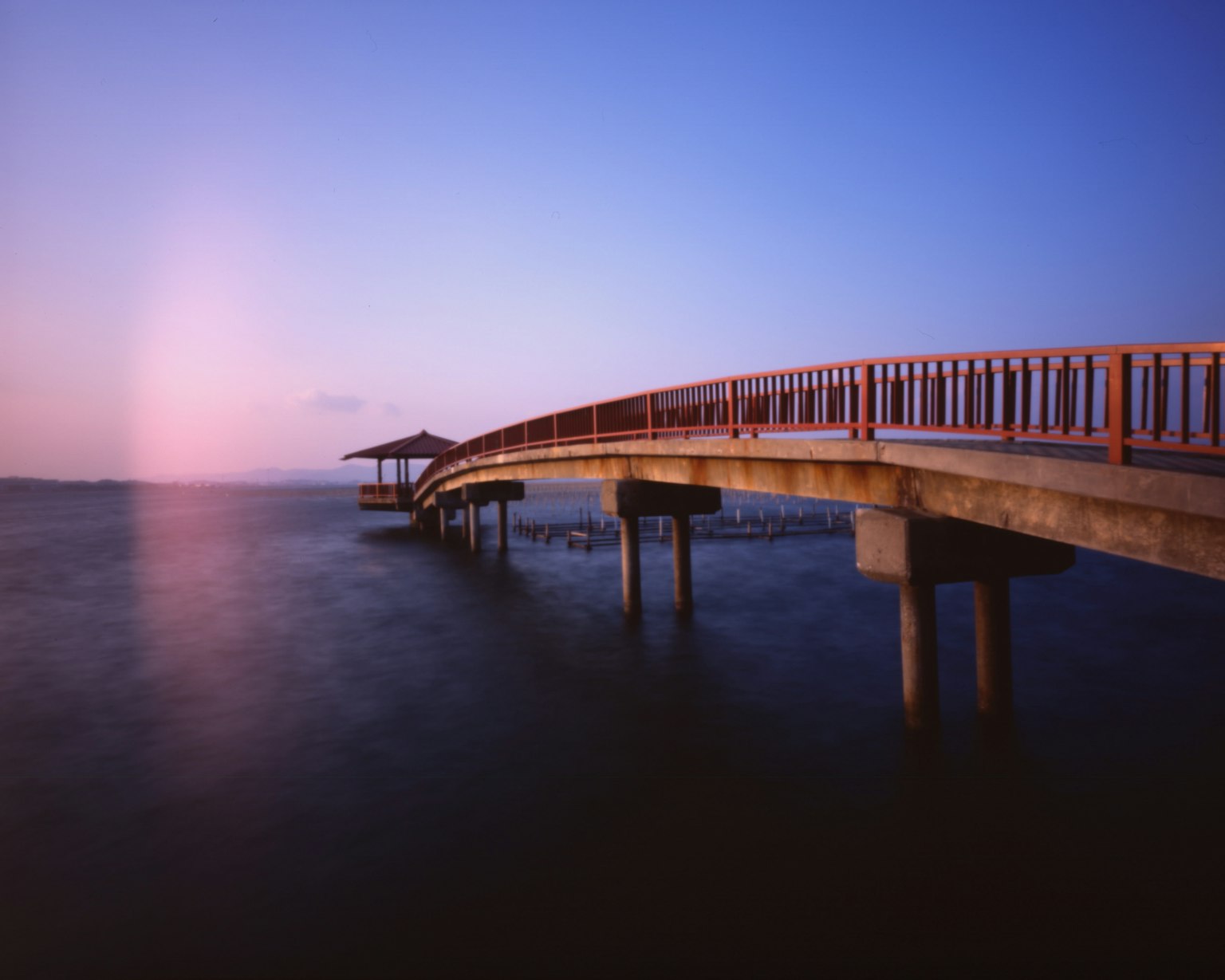 Wooden pier extending over calm waters under a blue sky