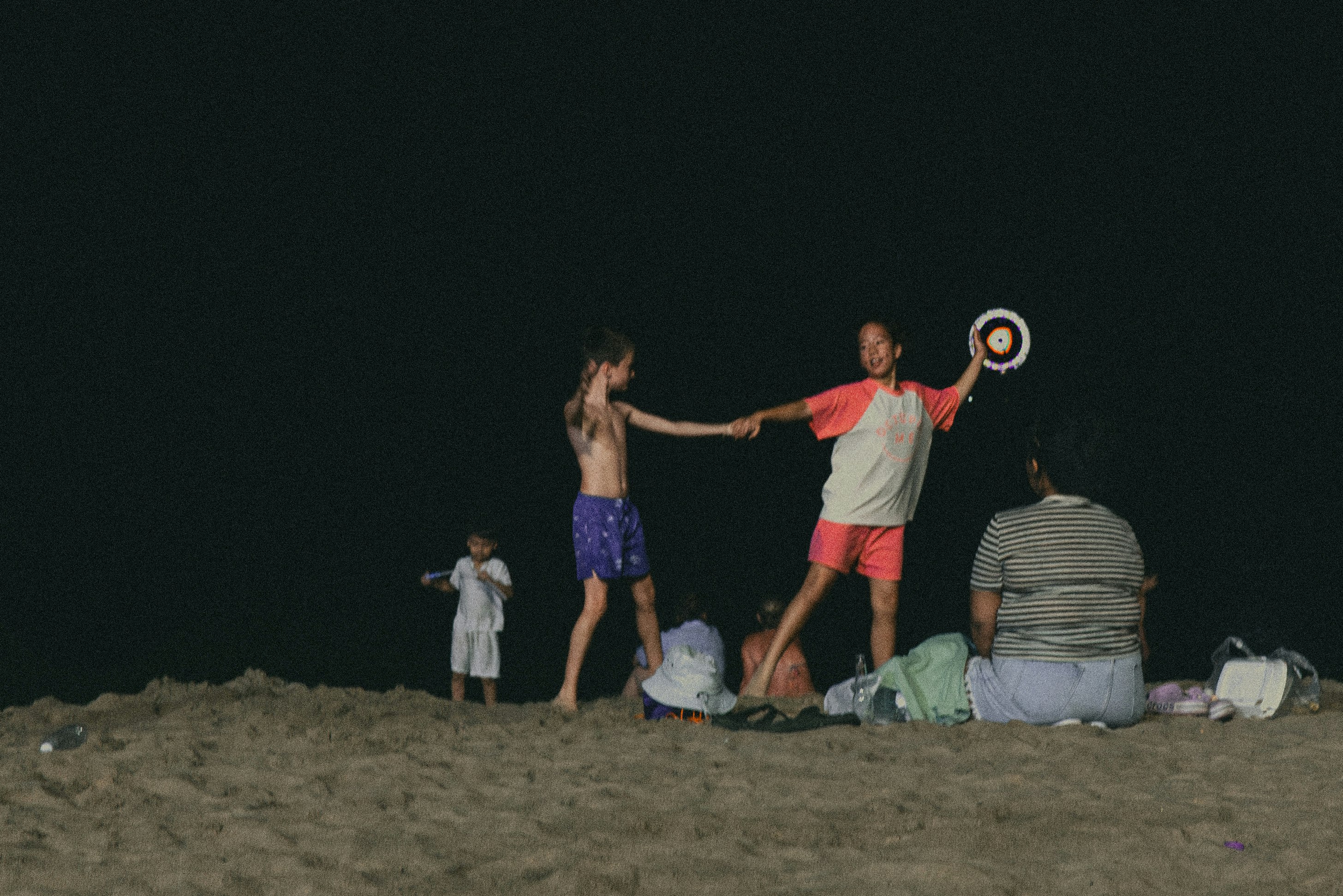 persone che giocano con una palla da spiaggia su una spiaggia notturna