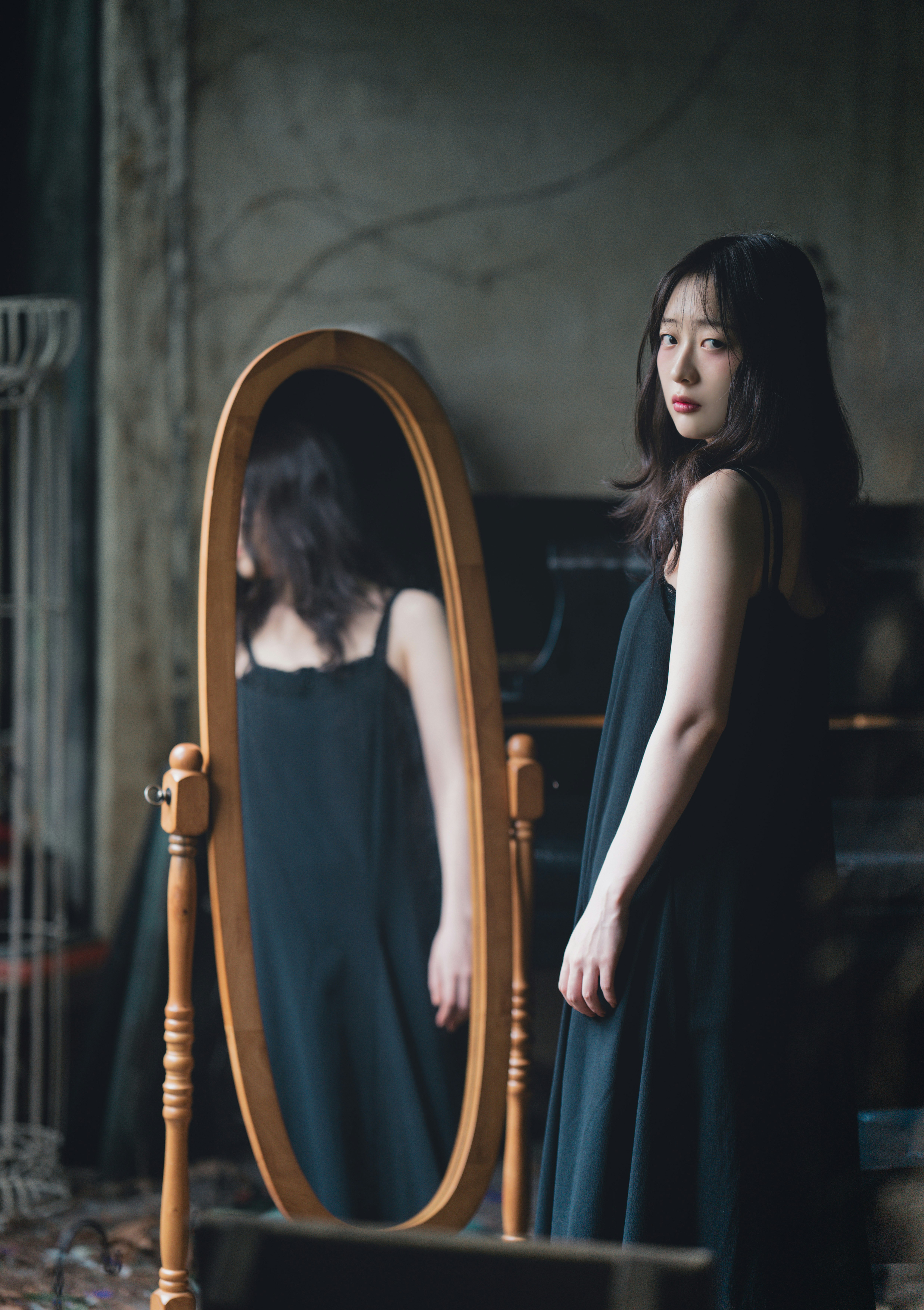 鏡の前に立つ黒いドレスの女性