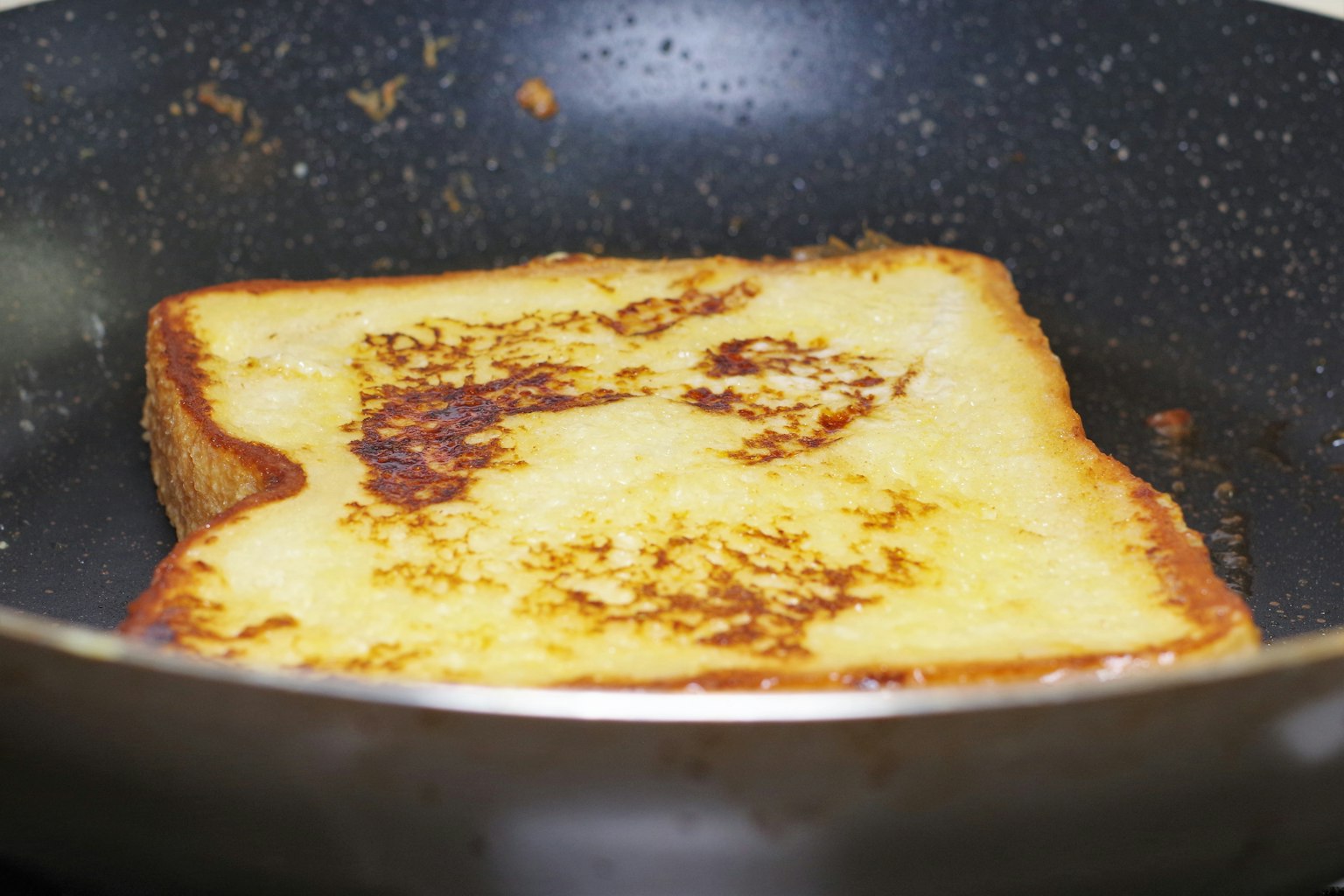Una fetta di toast francese che cuoce in una padella