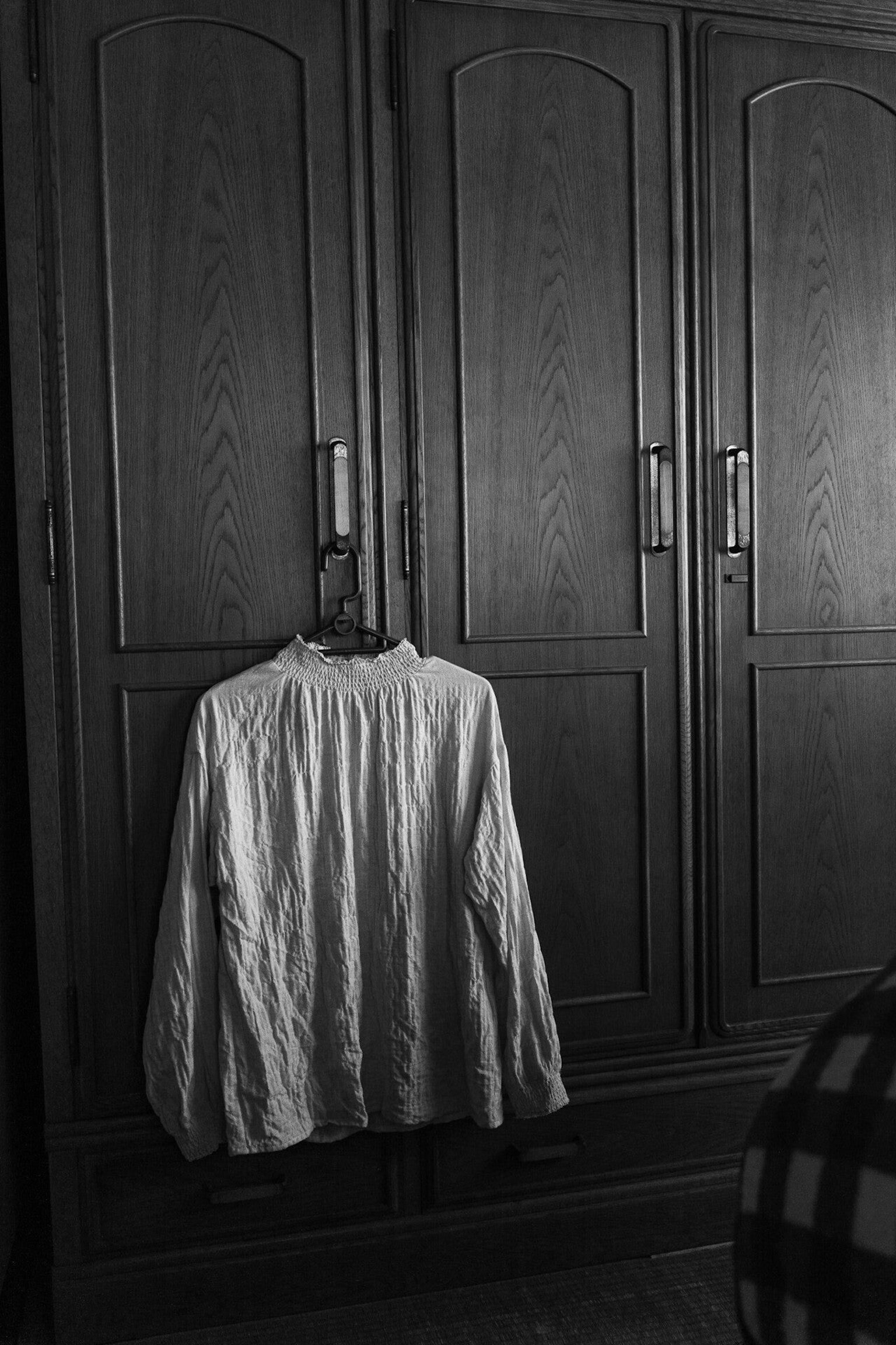 เสื้อเชิ้ตสีขาวแขวนอยู่บนตู้ไม้ในแบบขาวดำ