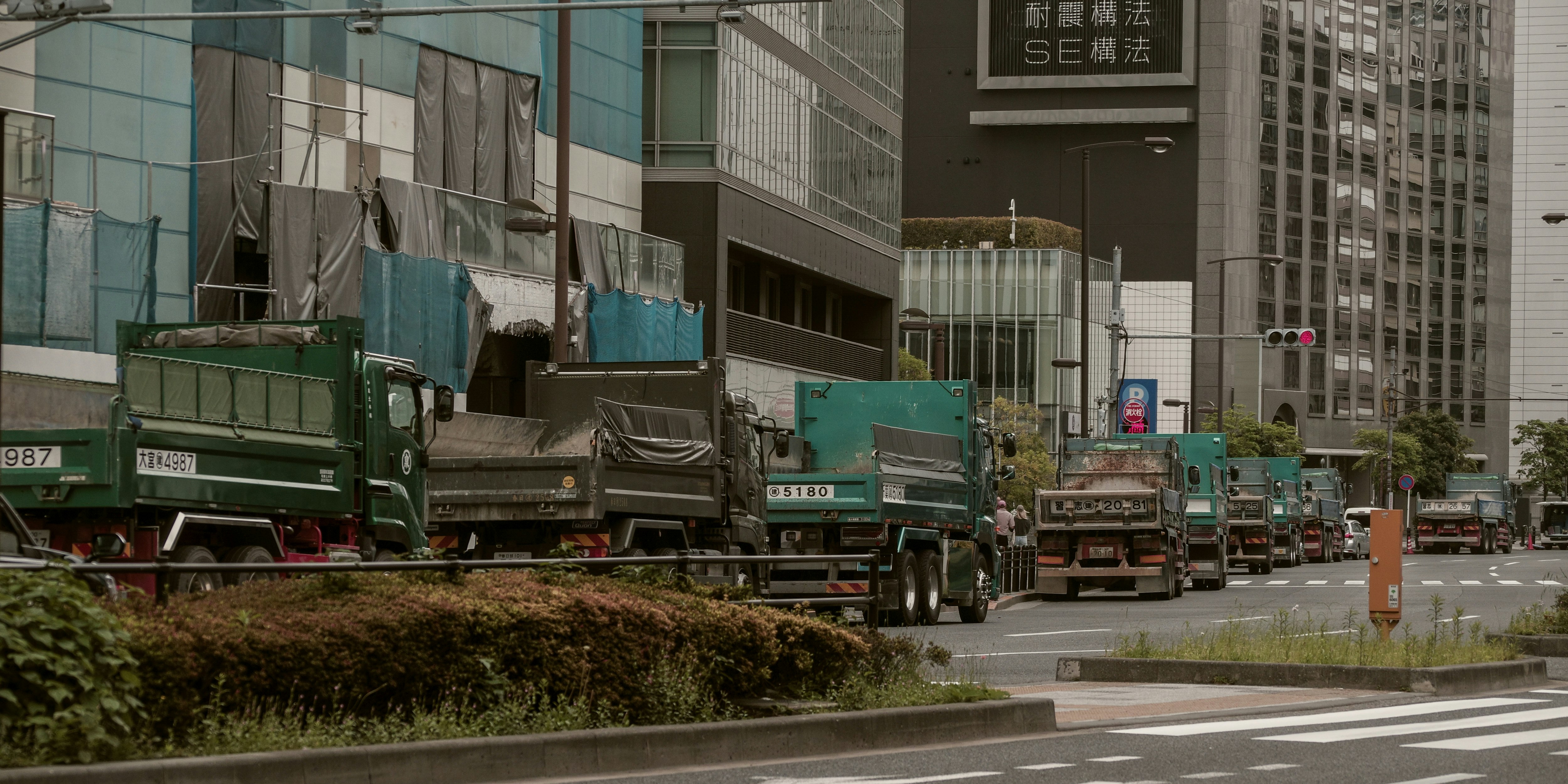 朝の街並みで待機するダンプトラックの列