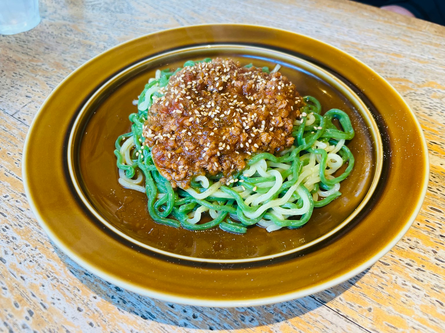 Piatto di noodle verdi con salsa di carne e semi di sesamo
