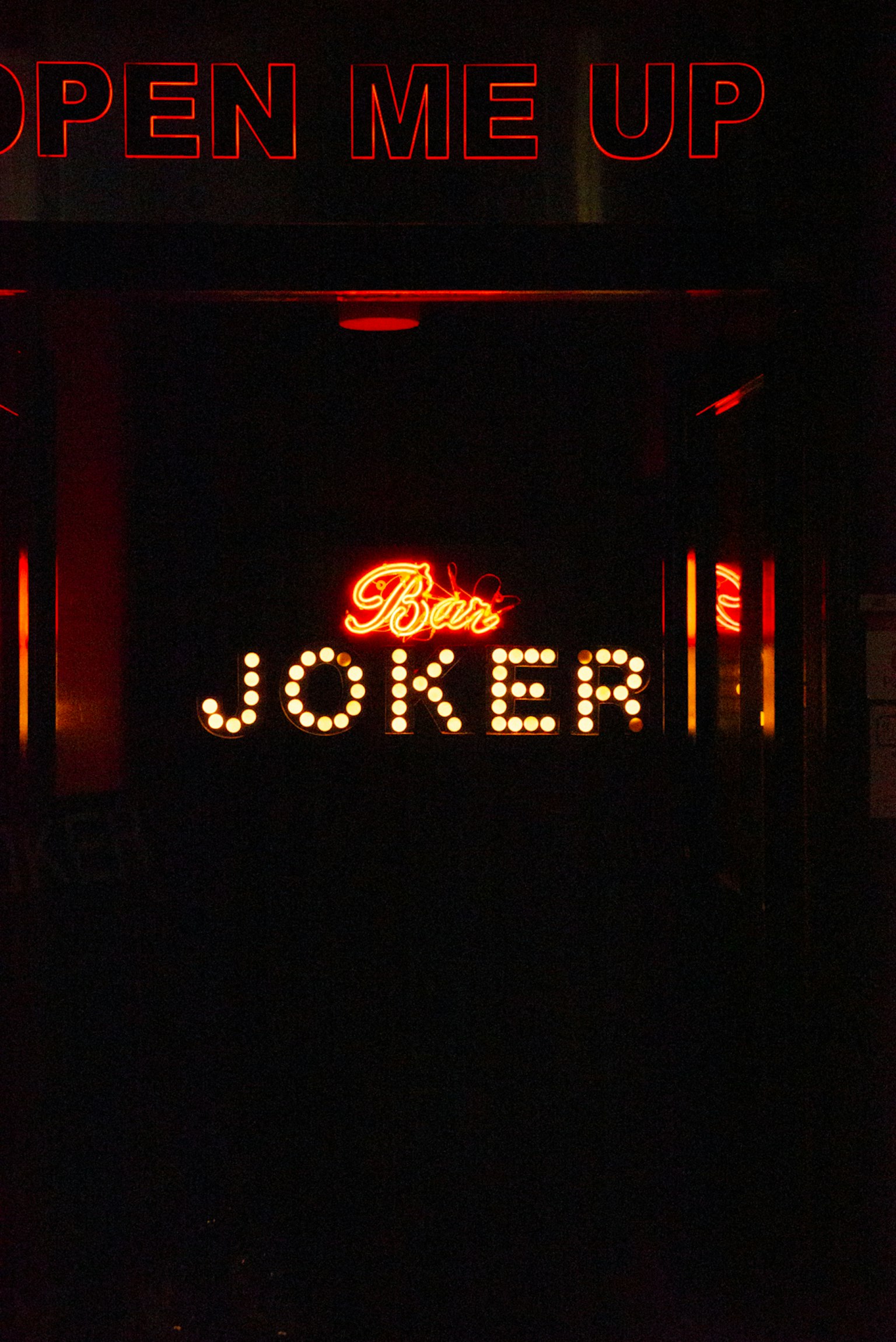 Tanda bercahaya yang bertuliskan JOKER dengan OPEN ME UP di atasnya