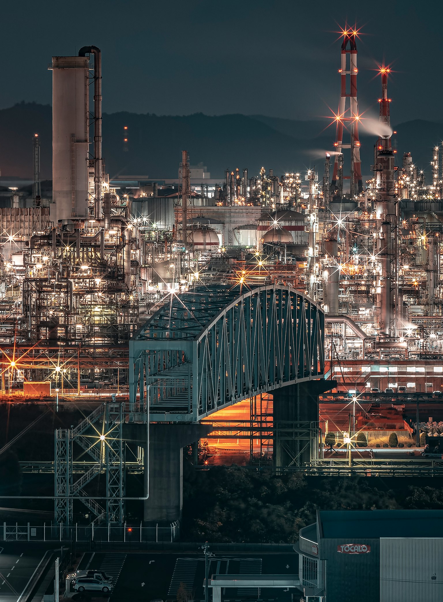 Vista notturna di un'area industriale con un ponte e fabbriche illuminate