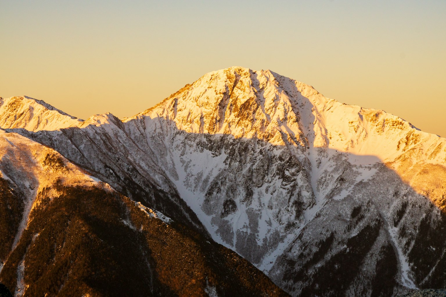Majestätischer Blick auf schneebedeckte Berge Sonnenuntergangslicht, das den Gipfel beleuchtet