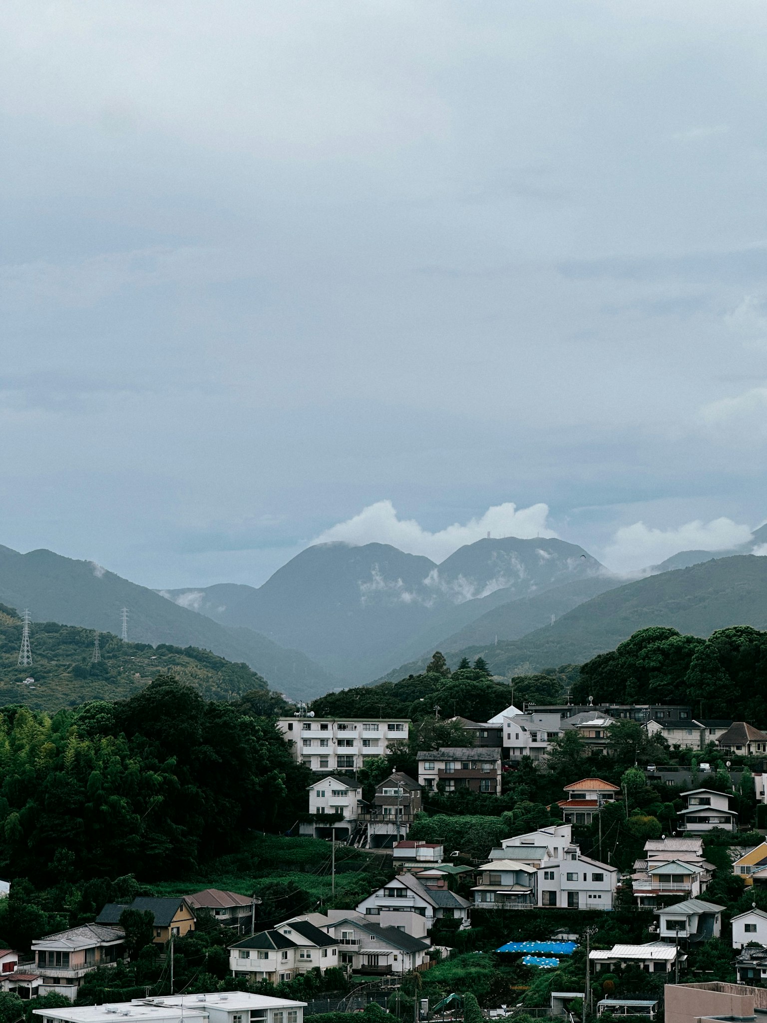 Pemandangan pegunungan dan rumah di bawah langit mendung