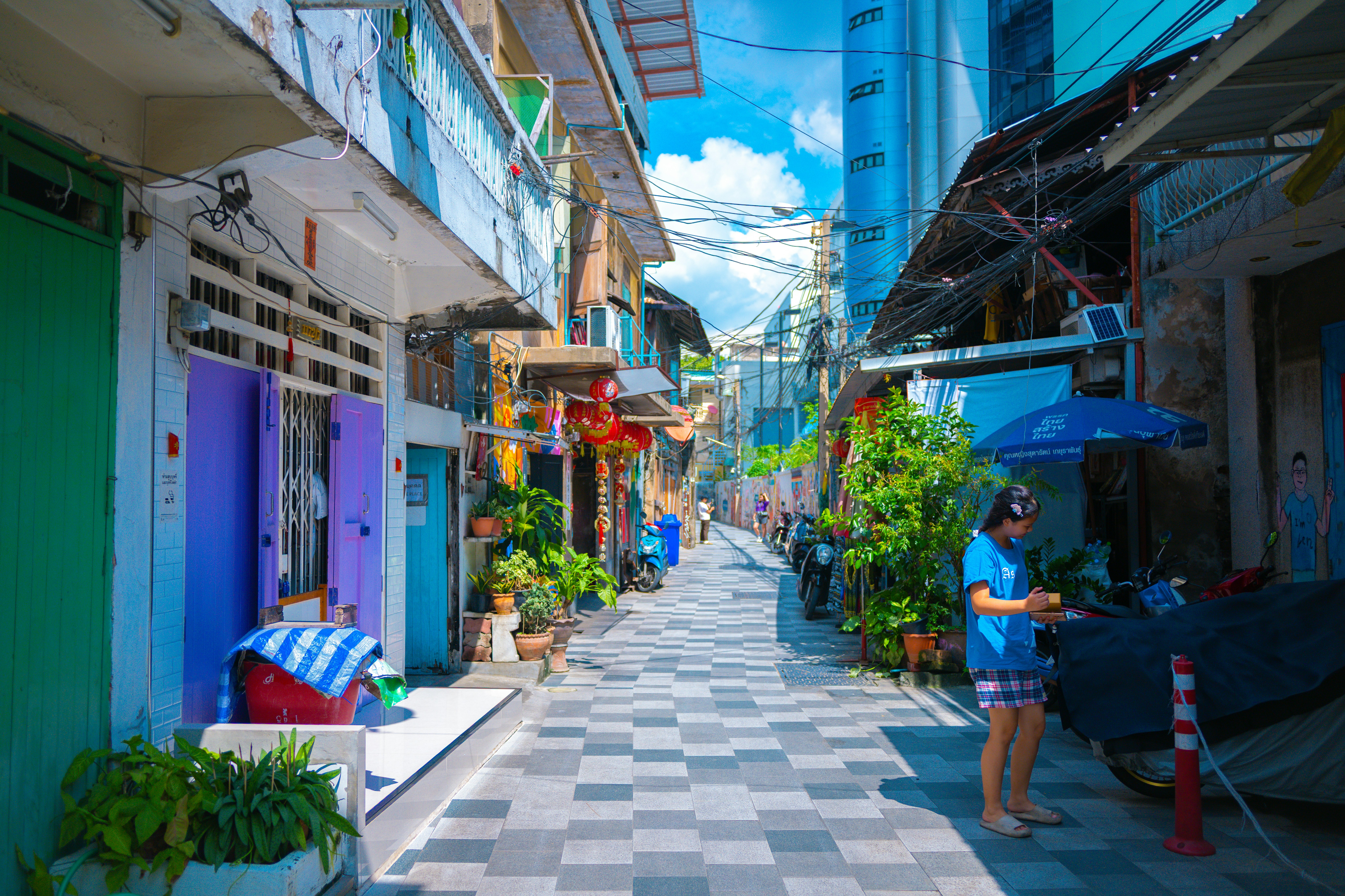 カラフルな路地の並ぶ商店街と植木、歩く人のある風景
