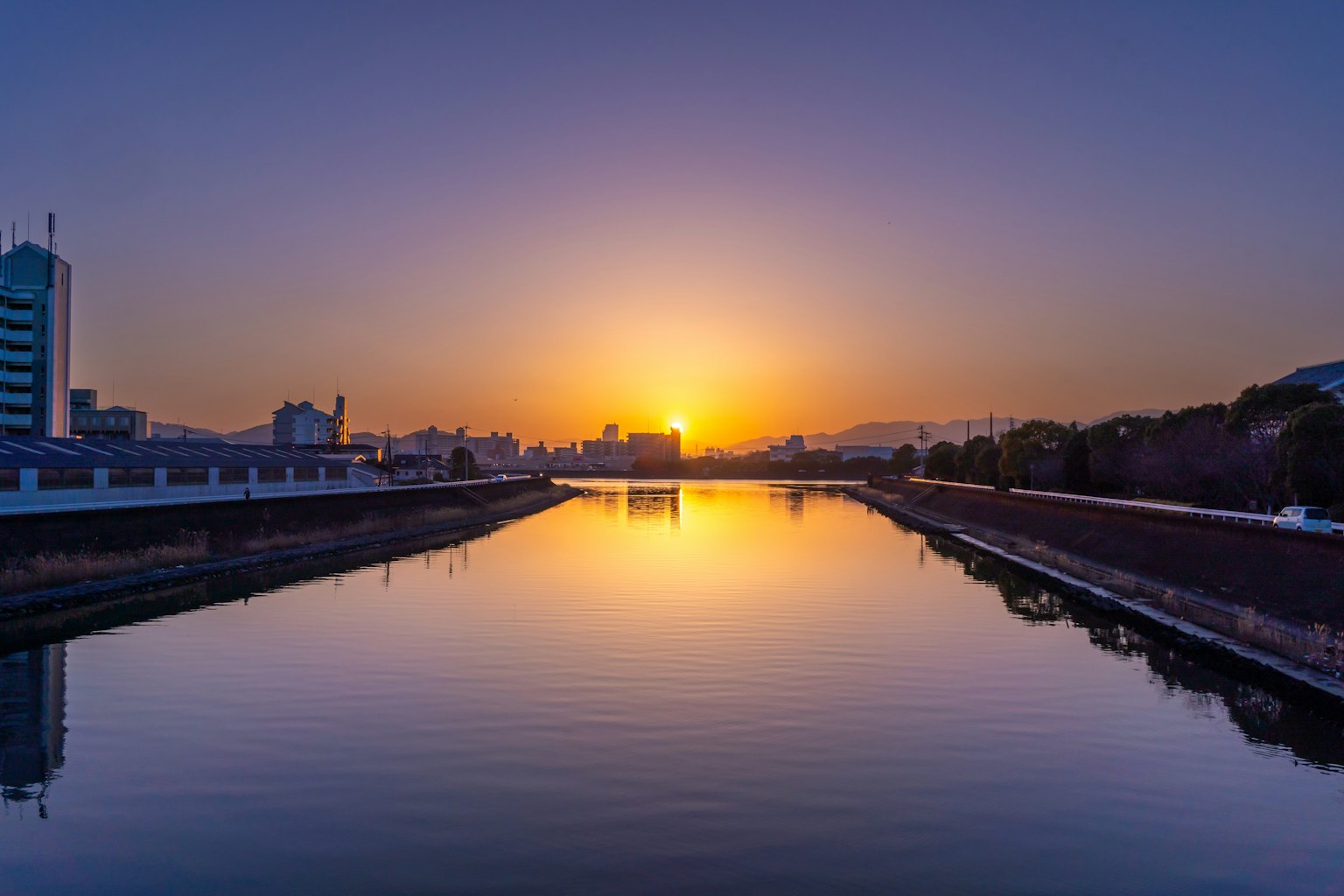 Atardecer sobre un río reflejando el horizonte urbano