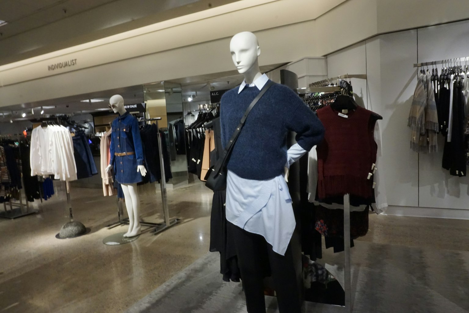 A mannequin in a store wearing a blue sweater and a white apron