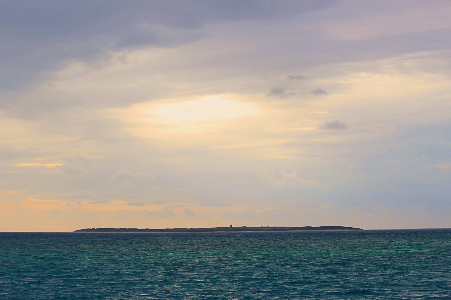 Paysage maritime avec des eaux calmes et une île lointaine sous un ciel nuageux