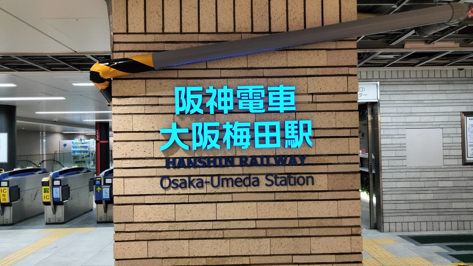 Schild der Osaka Umeda Station mit dem blauen Logo der Hanshin-Bahn