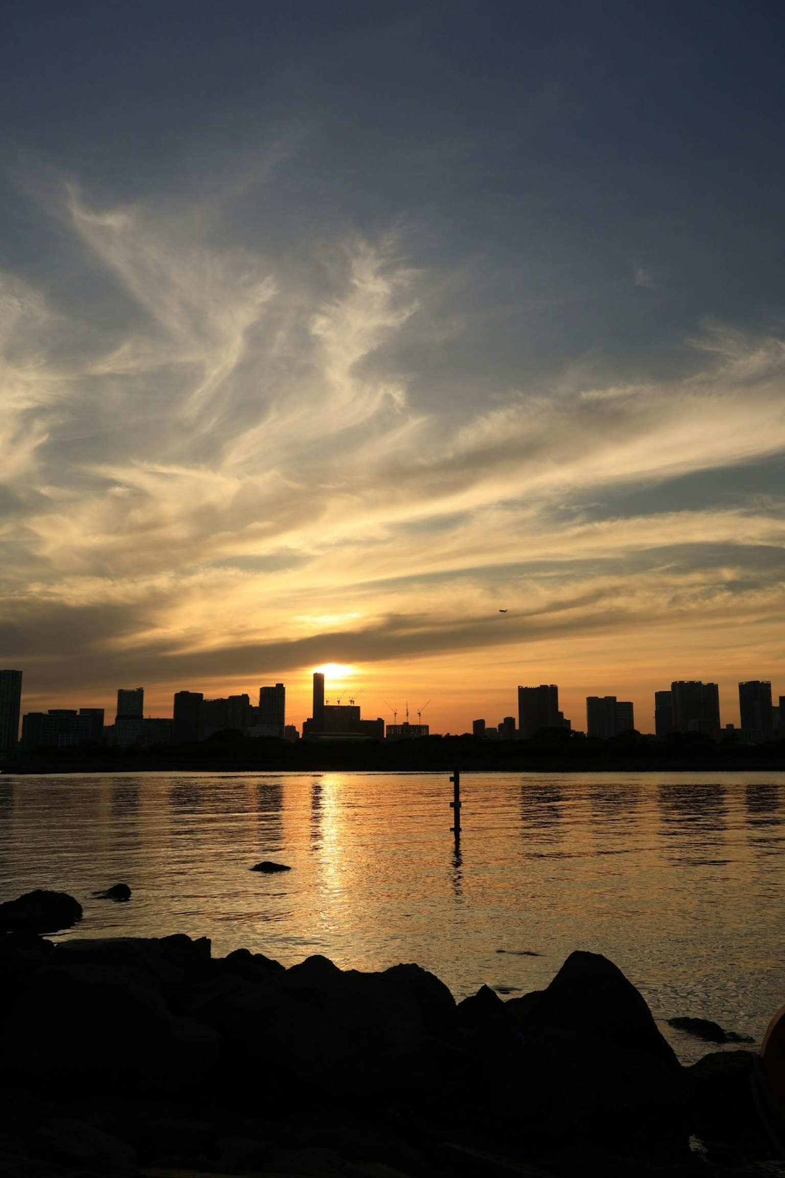 Silueta de una ciudad al atardecer reflejada en el agua