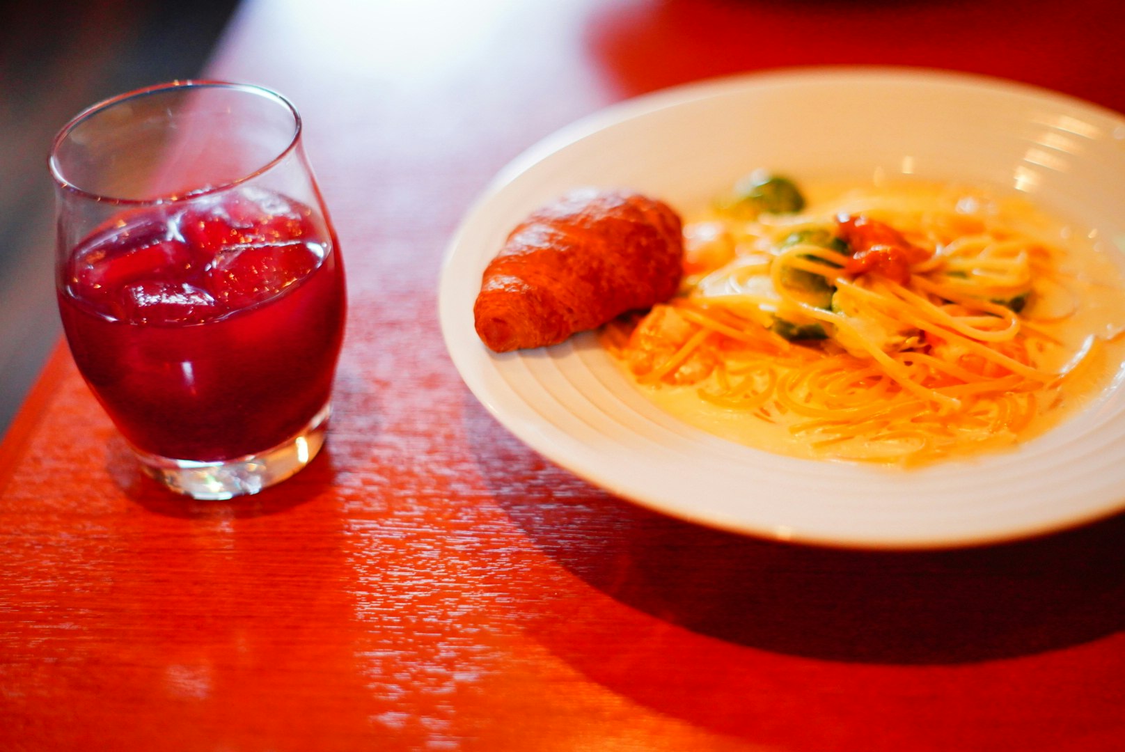 赤い飲み物とイタリアンのパスタが並ぶランチプレート