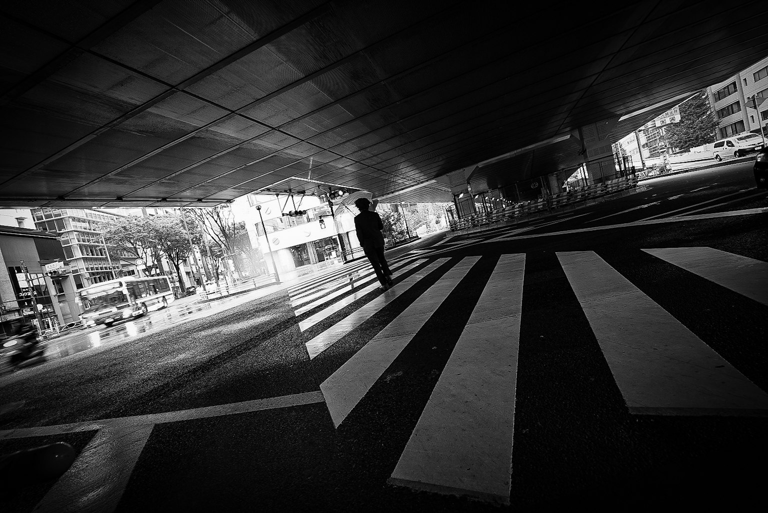 Silhouette d'une personne marchant sur un passage piéton en noir et blanc paysage urbain avec des reflets visibles