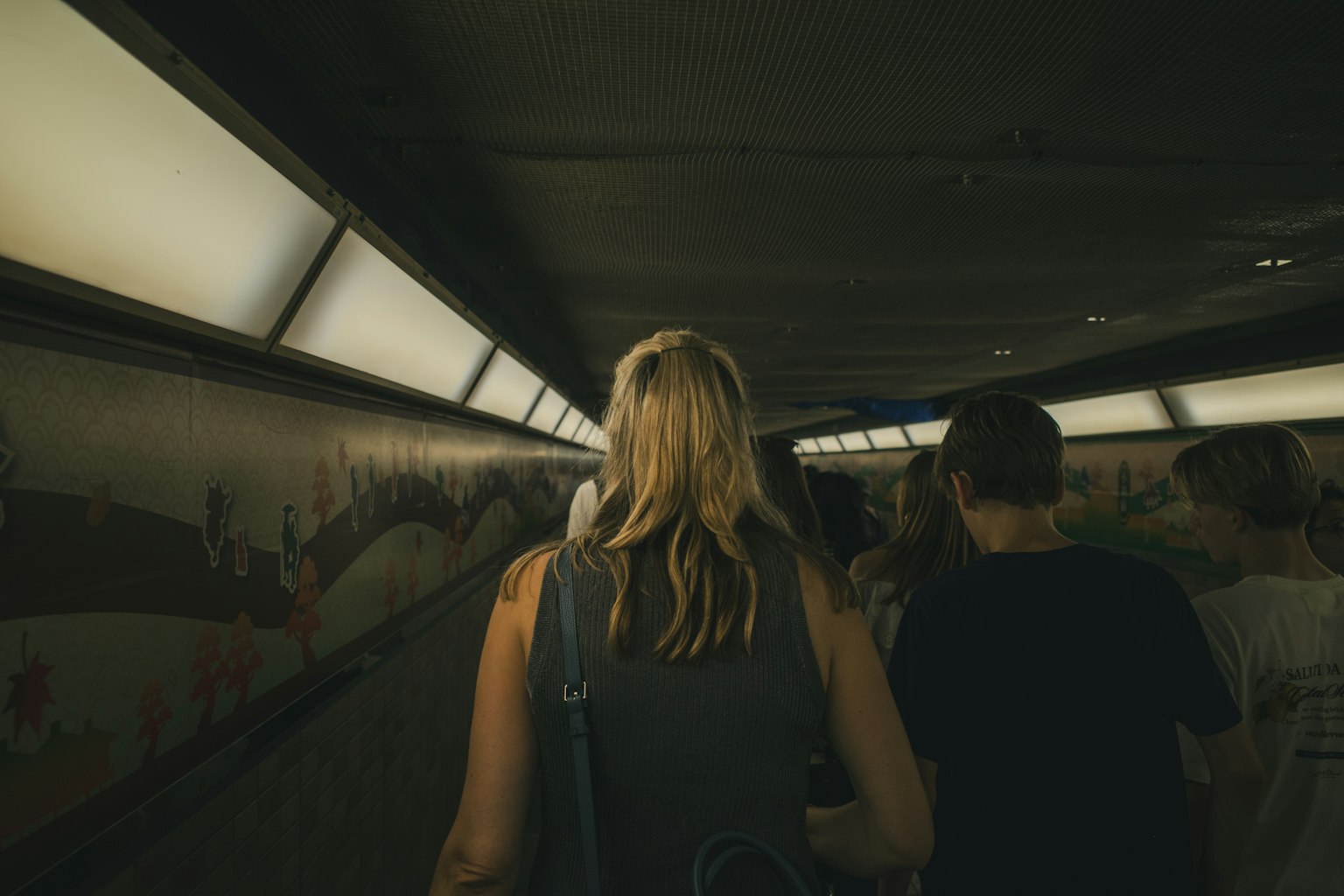Menschen gehen durch einen Tunnel mit hellem Licht und Wandkunst