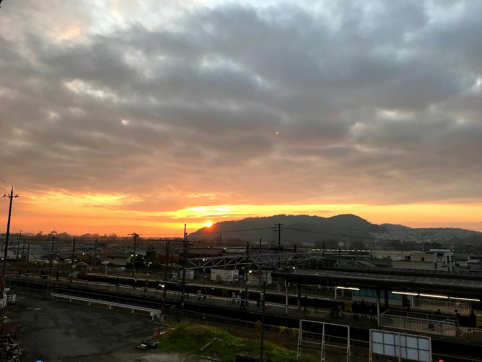 日落天空與山脈輪廓的風景，前面有可見的鐵路軌道