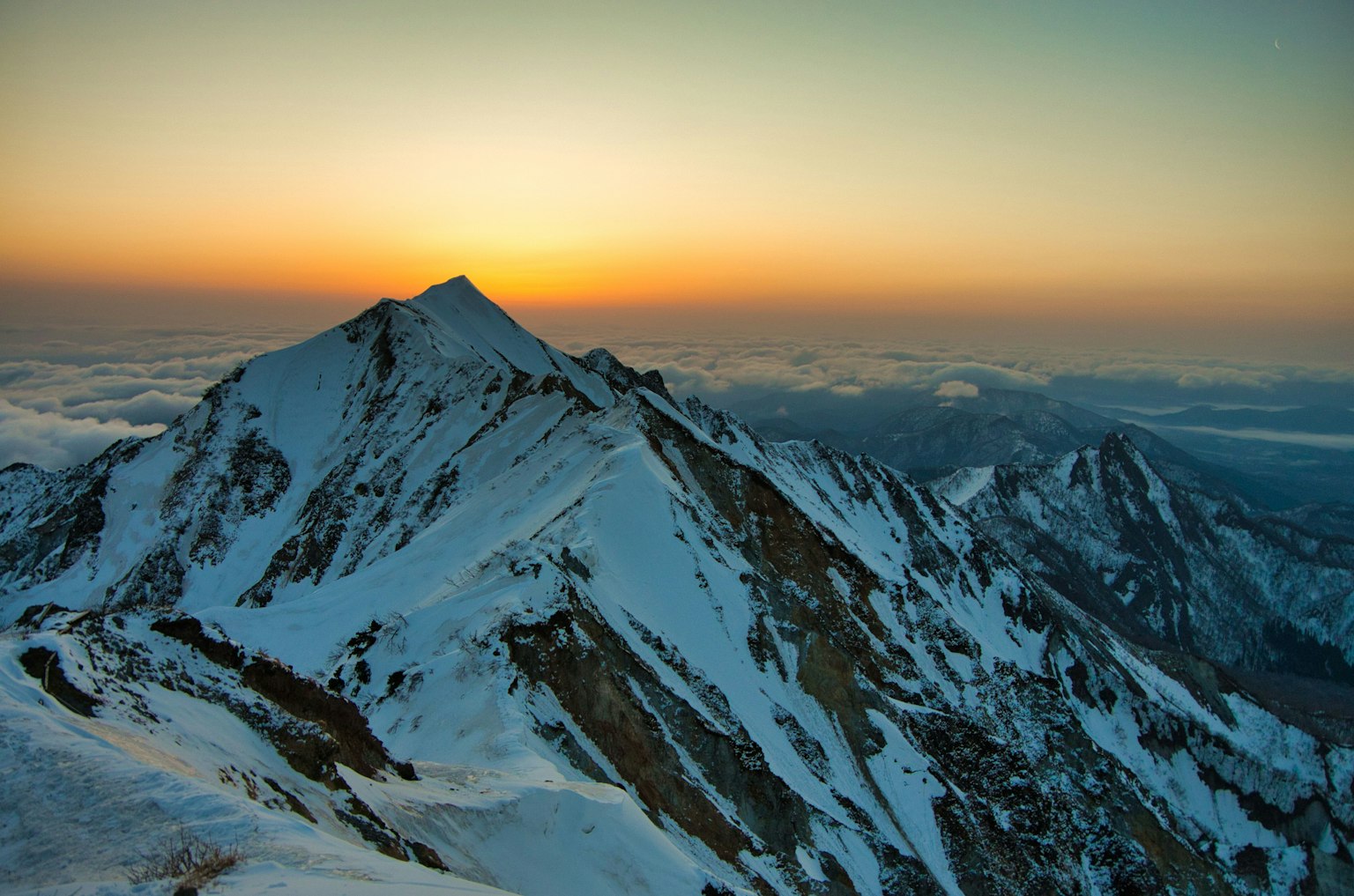 Snow-covered mountain peaks with a sunset backdrop
