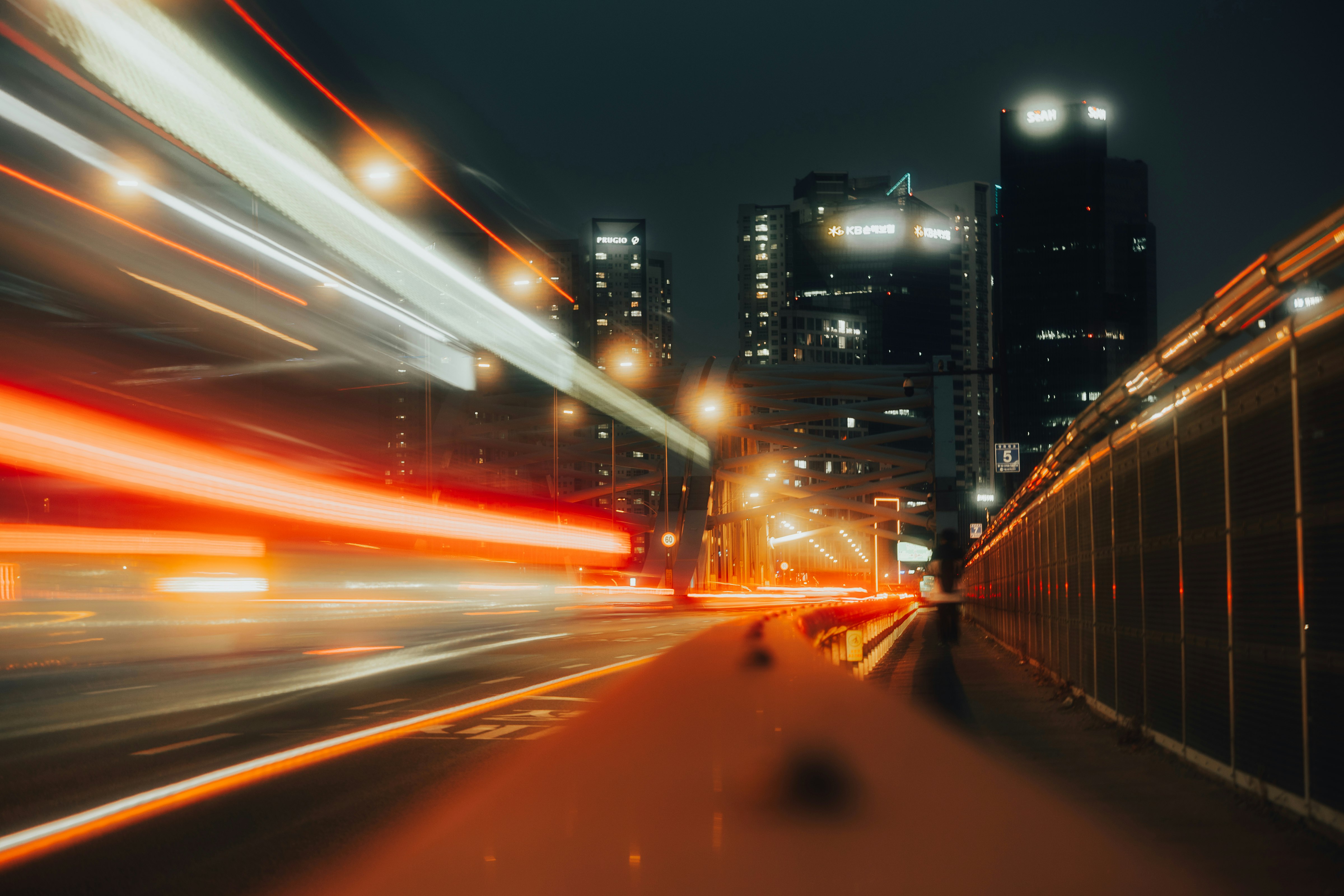 夜の高速道路を走る車の光跡と高層ビルの夜景