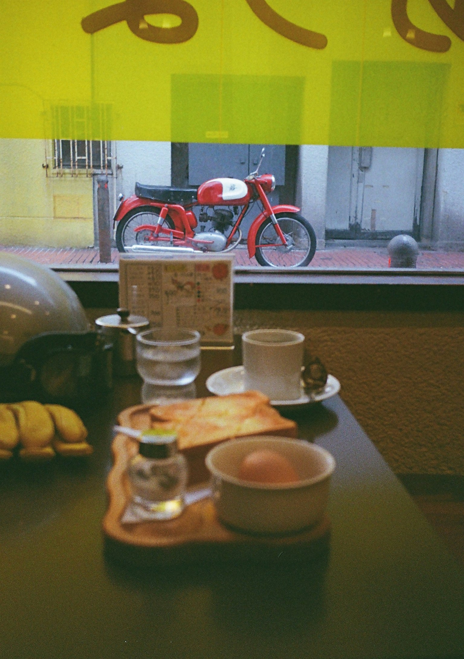 Bữa sáng trên bàn cạnh cửa sổ với xe máy đỏ bên ngoài