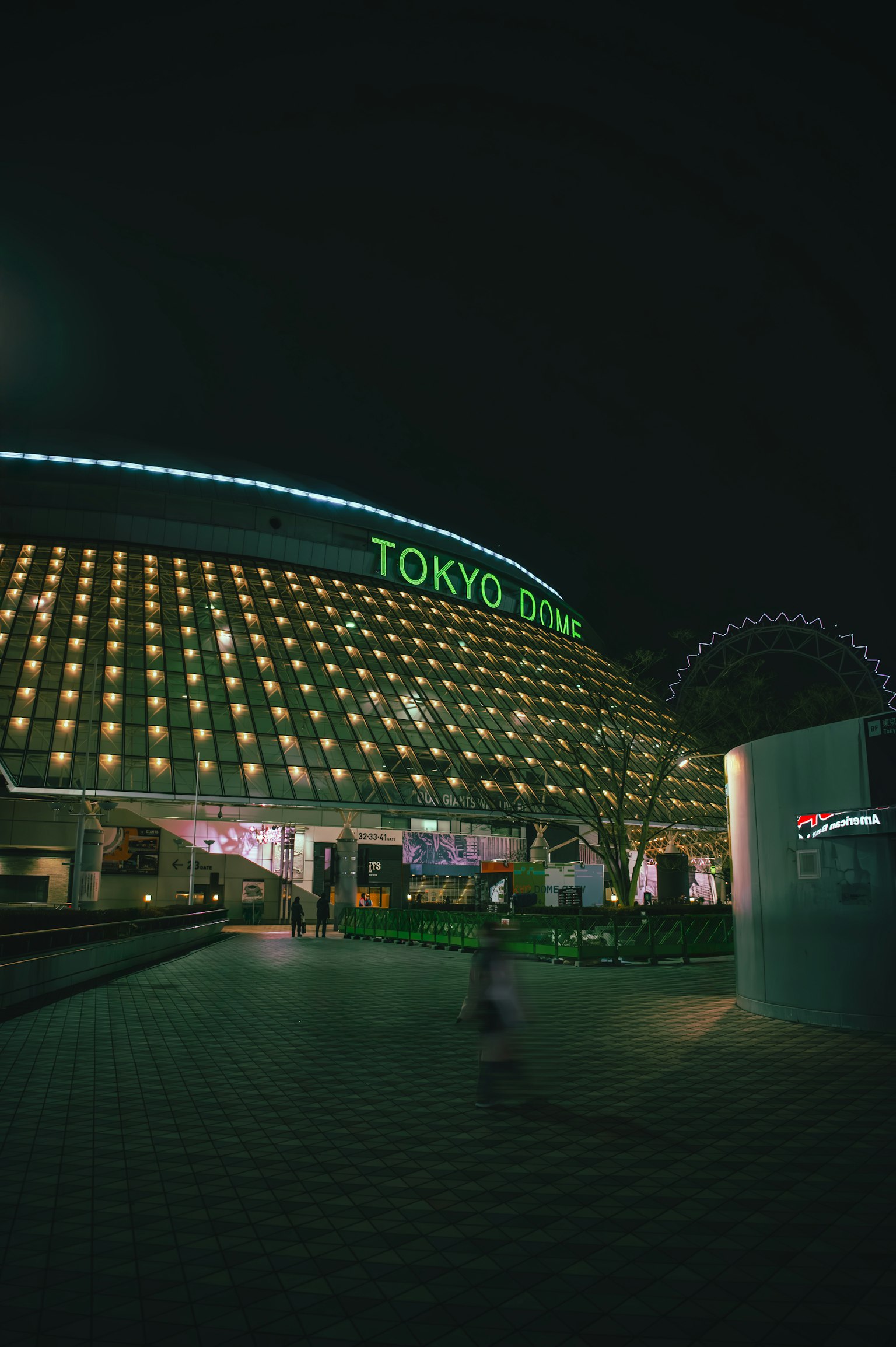 Tòa nhà sáng với biển hiệu Tokyo Zone và vòng quay khổng lồ vào ban đêm