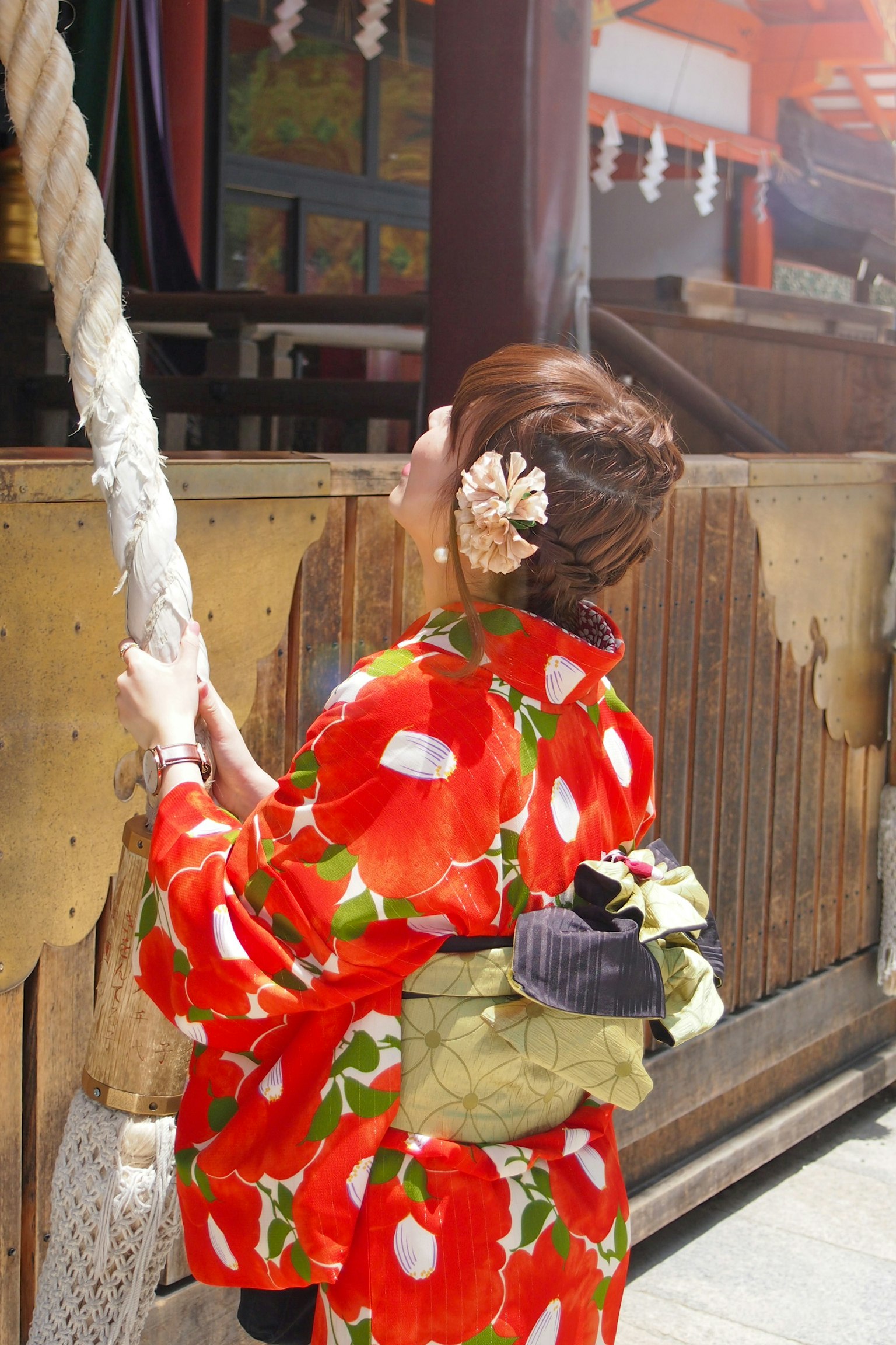Perempuan dalam kimono floral merah memegang lonceng tali