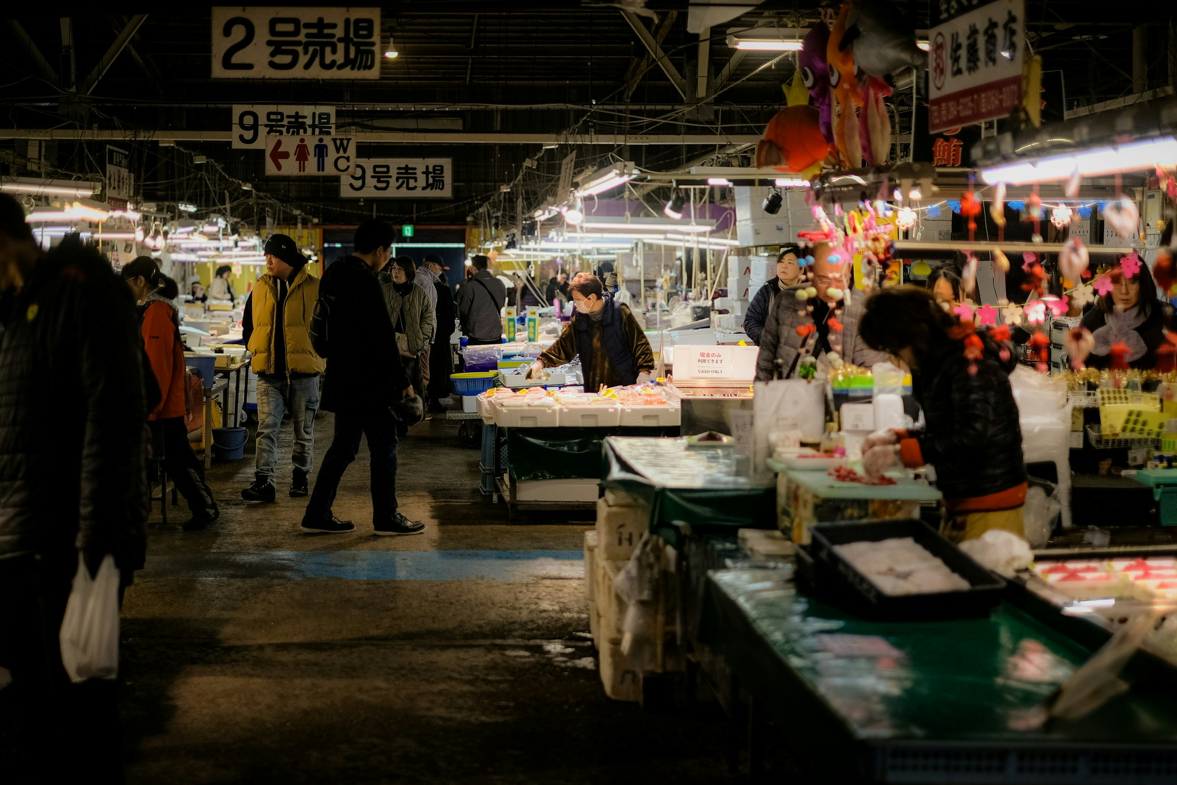 塩釜水産物仲卸市場の屋内で並ぶ海産物の屋台と買い物客