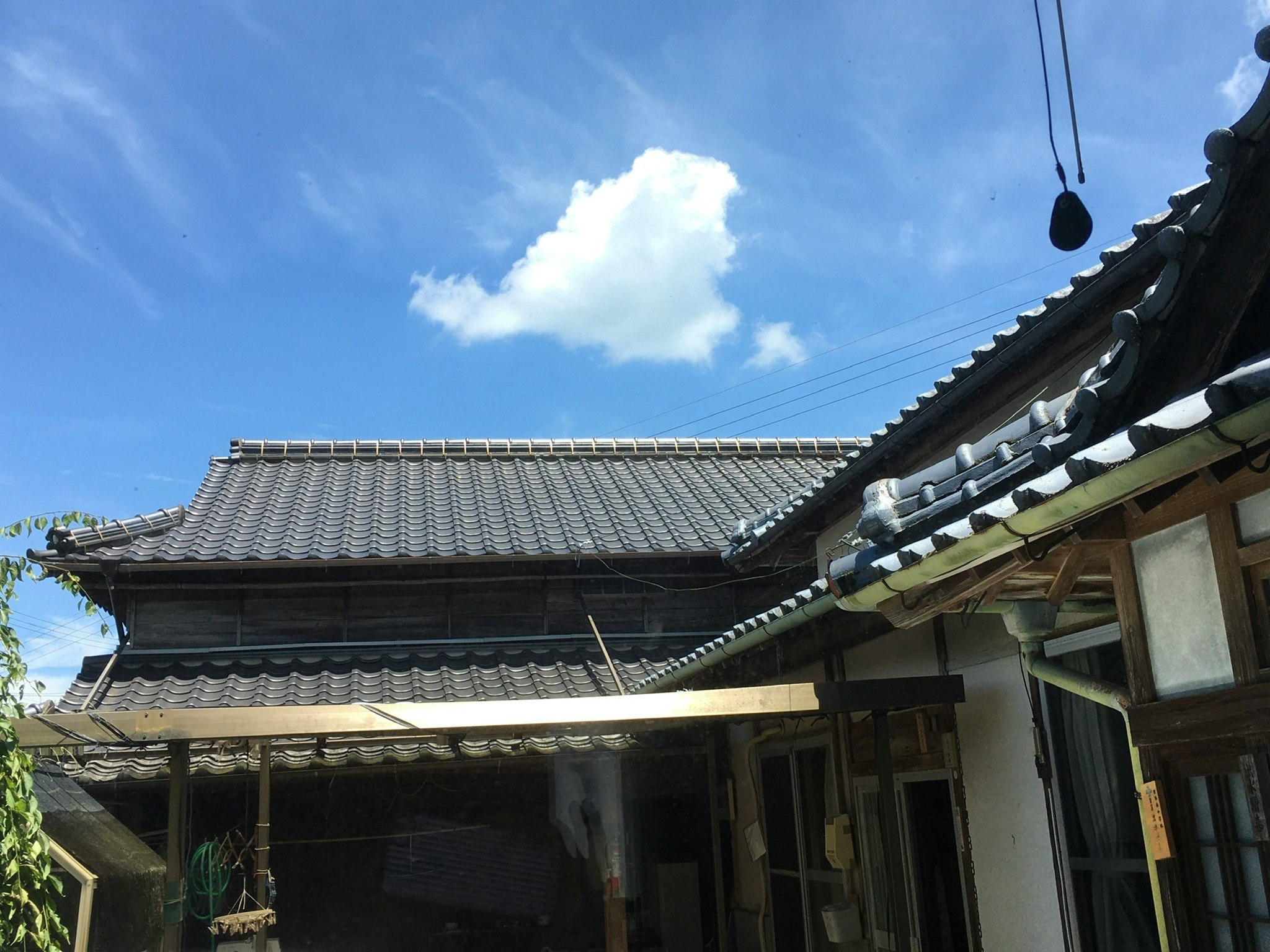 clouds over a traditional tiled roof and eaves under a blue sky