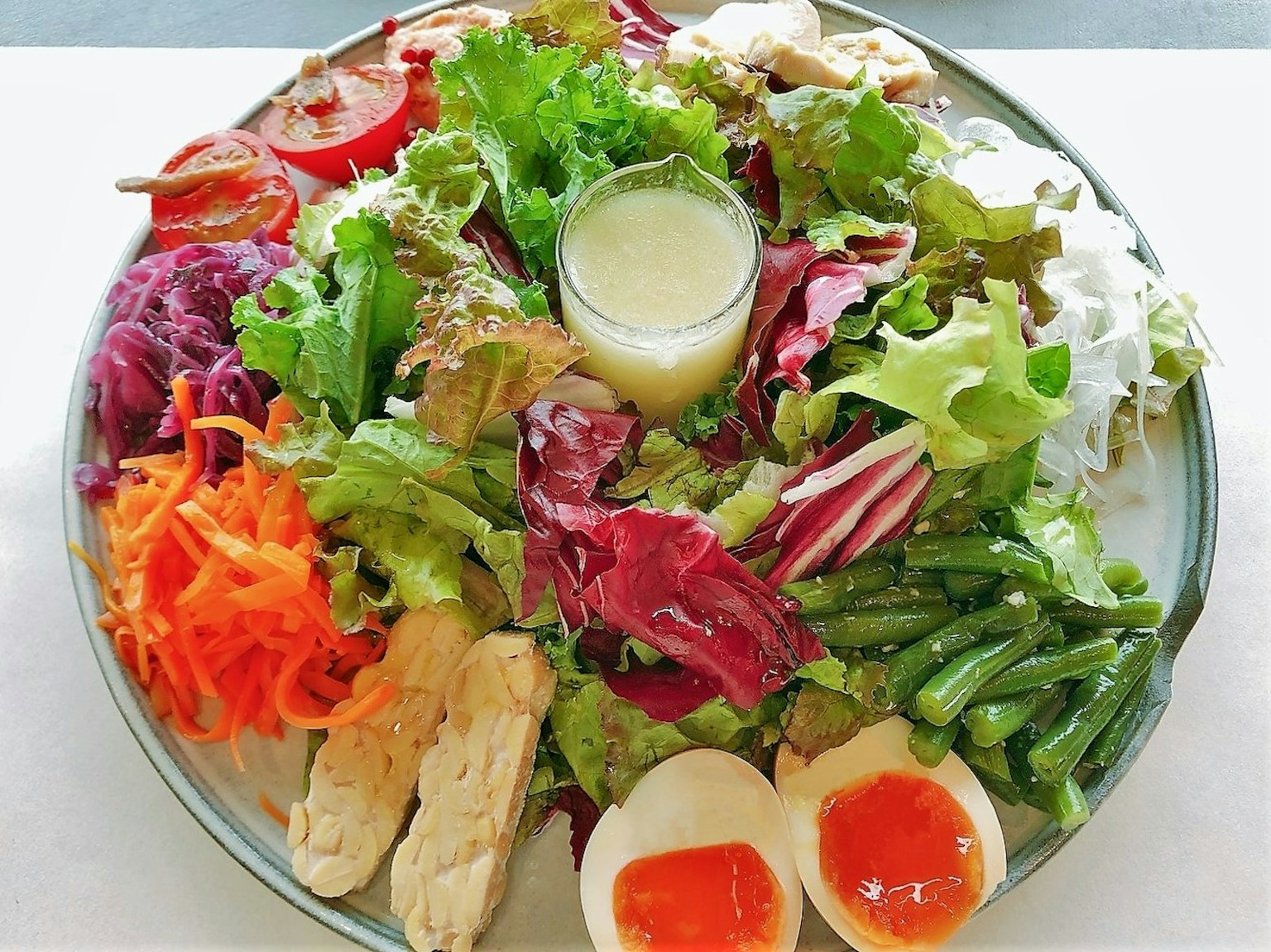 จานสลัดที่มีสีสันสดใสประกอบด้วยผักสด, เนื้อไก่, และไข่ต้ม