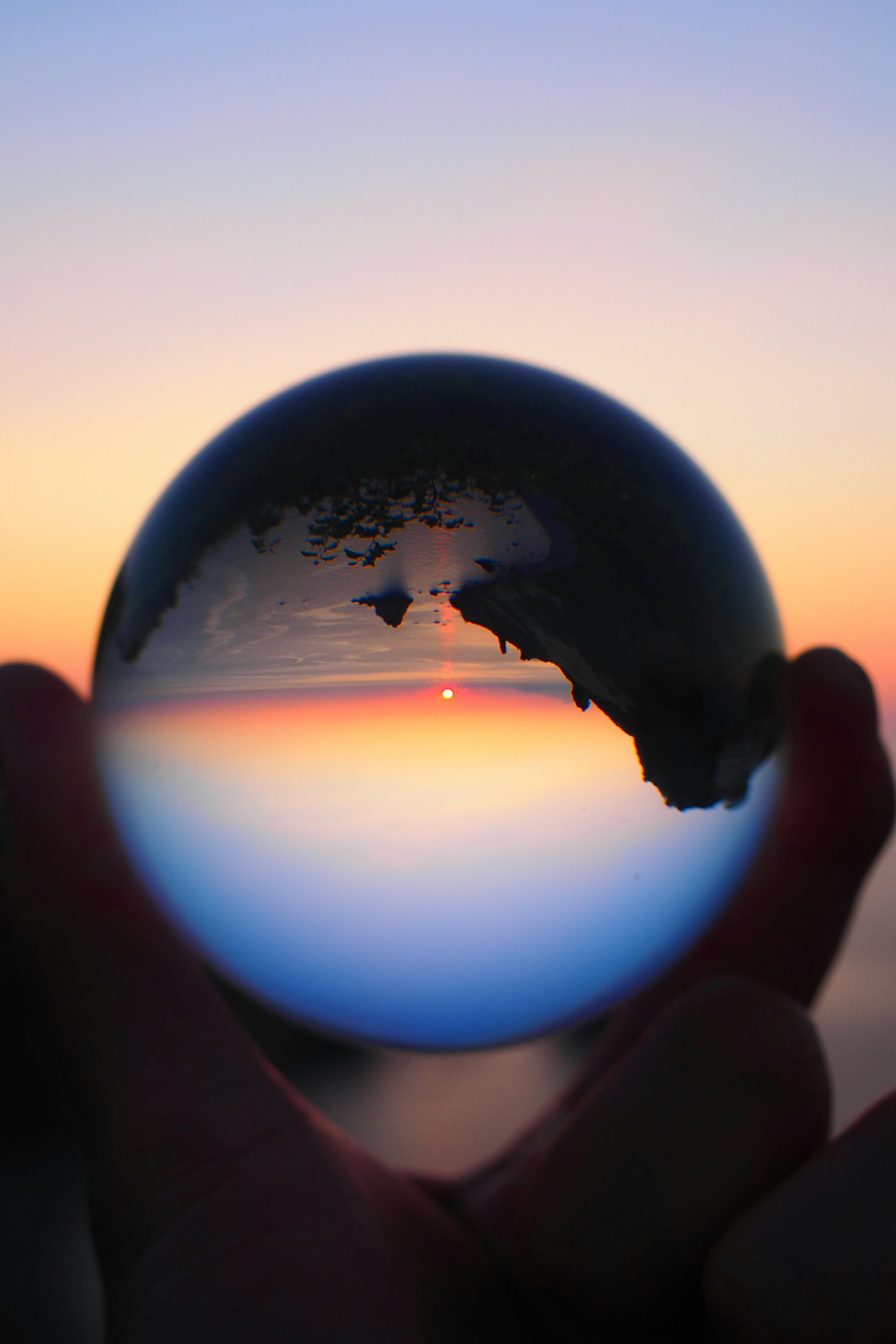 Silhouette holding a crystal ball reflecting a sunset