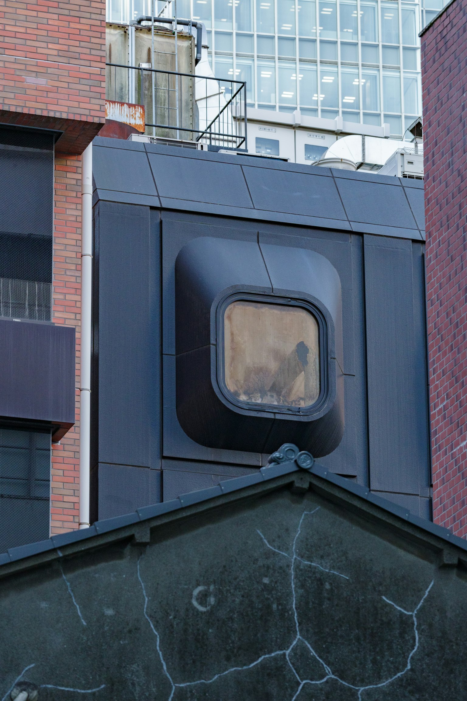 Fenêtre de forme unique sur un bâtiment moderne avec des structures environnantes