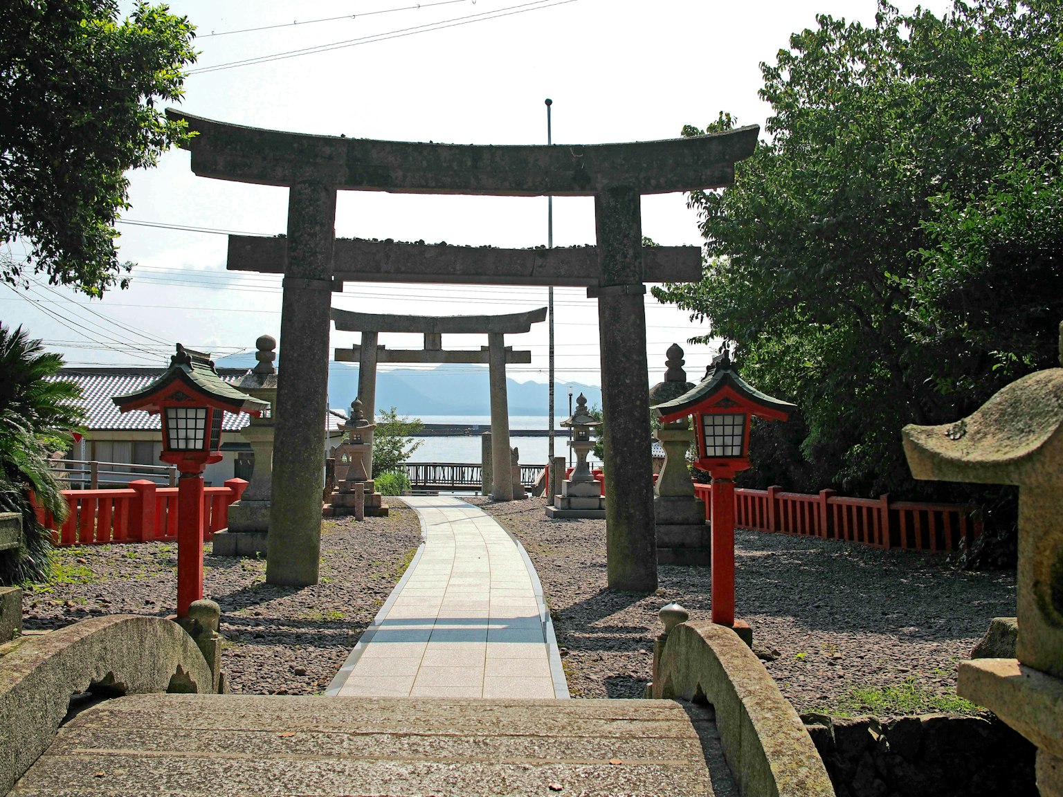 Vista escénica de un santuario con torii y faroles rojos