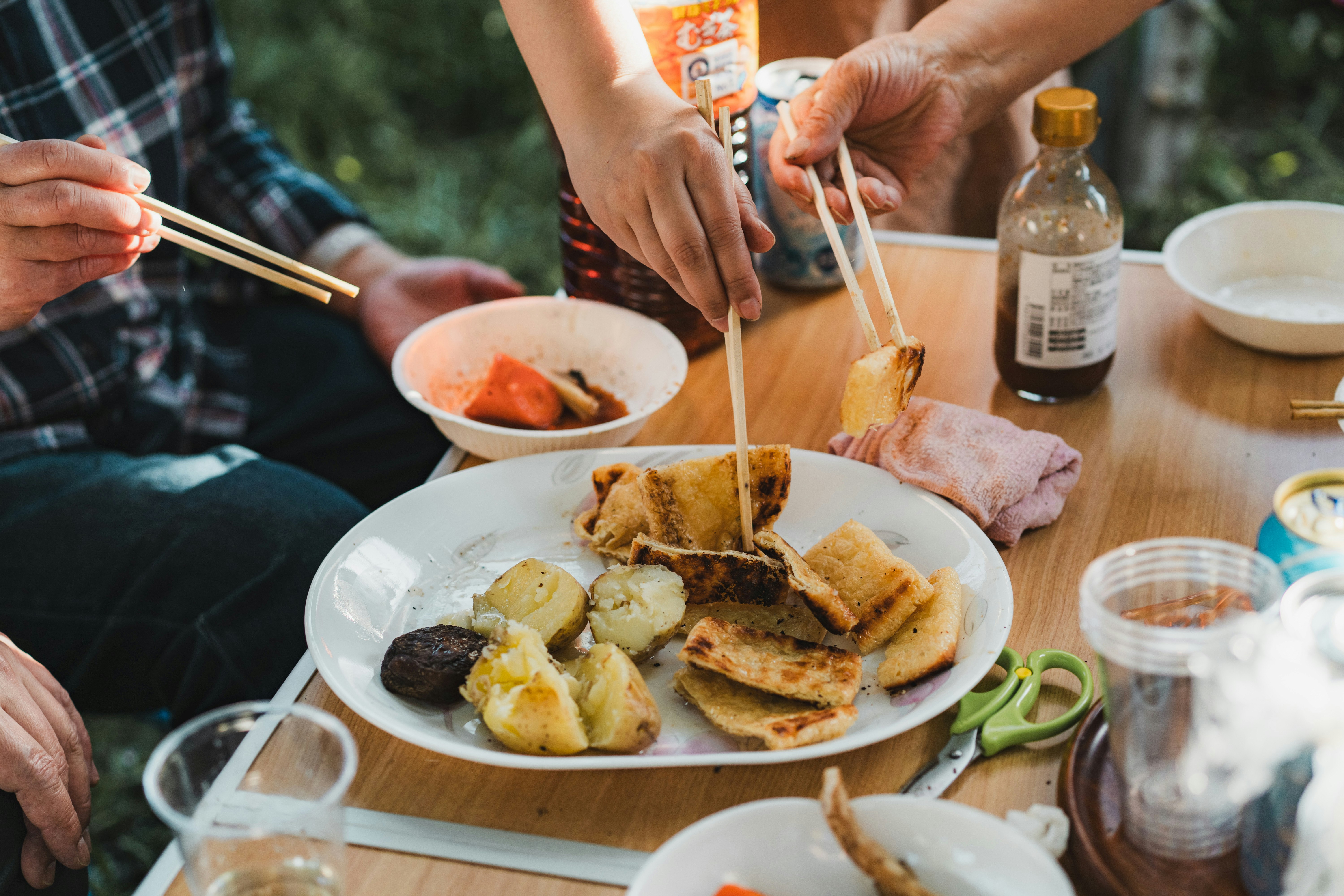 木のテーブルで取り分けられる揚げ物とスープの食卓