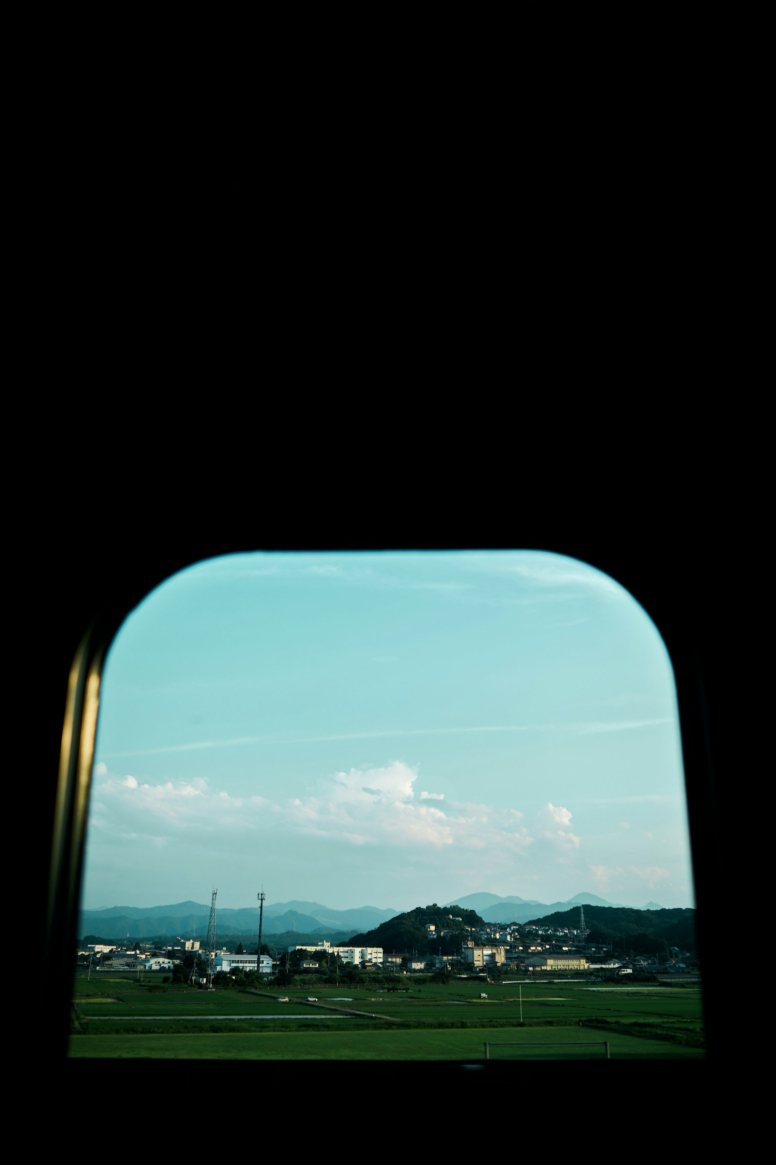 Pemandangan dari jendela kereta dengan langit biru dan gunung