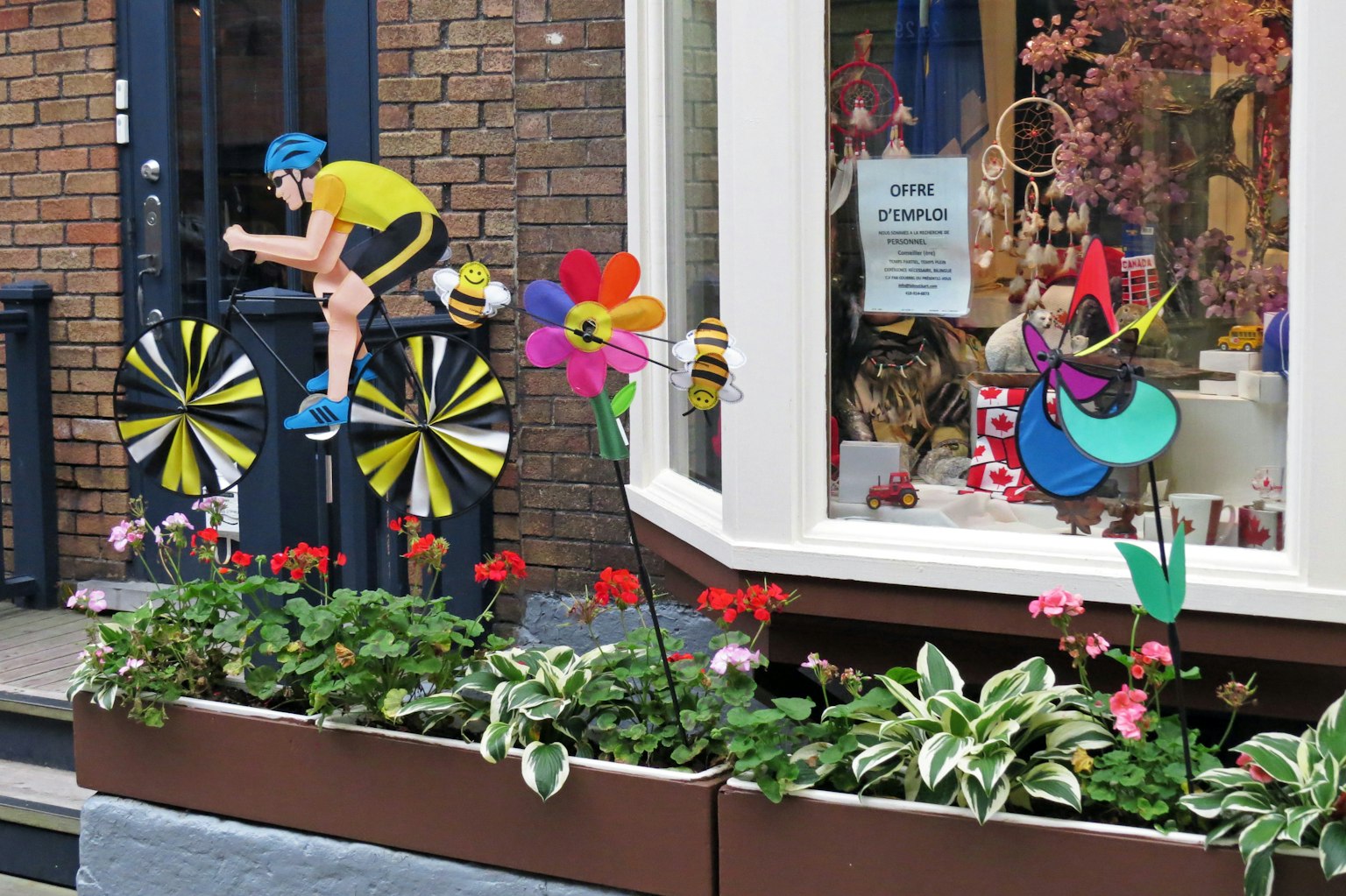Una vetrina con una decorazione di ciclista e fiori colorati in un vaso
