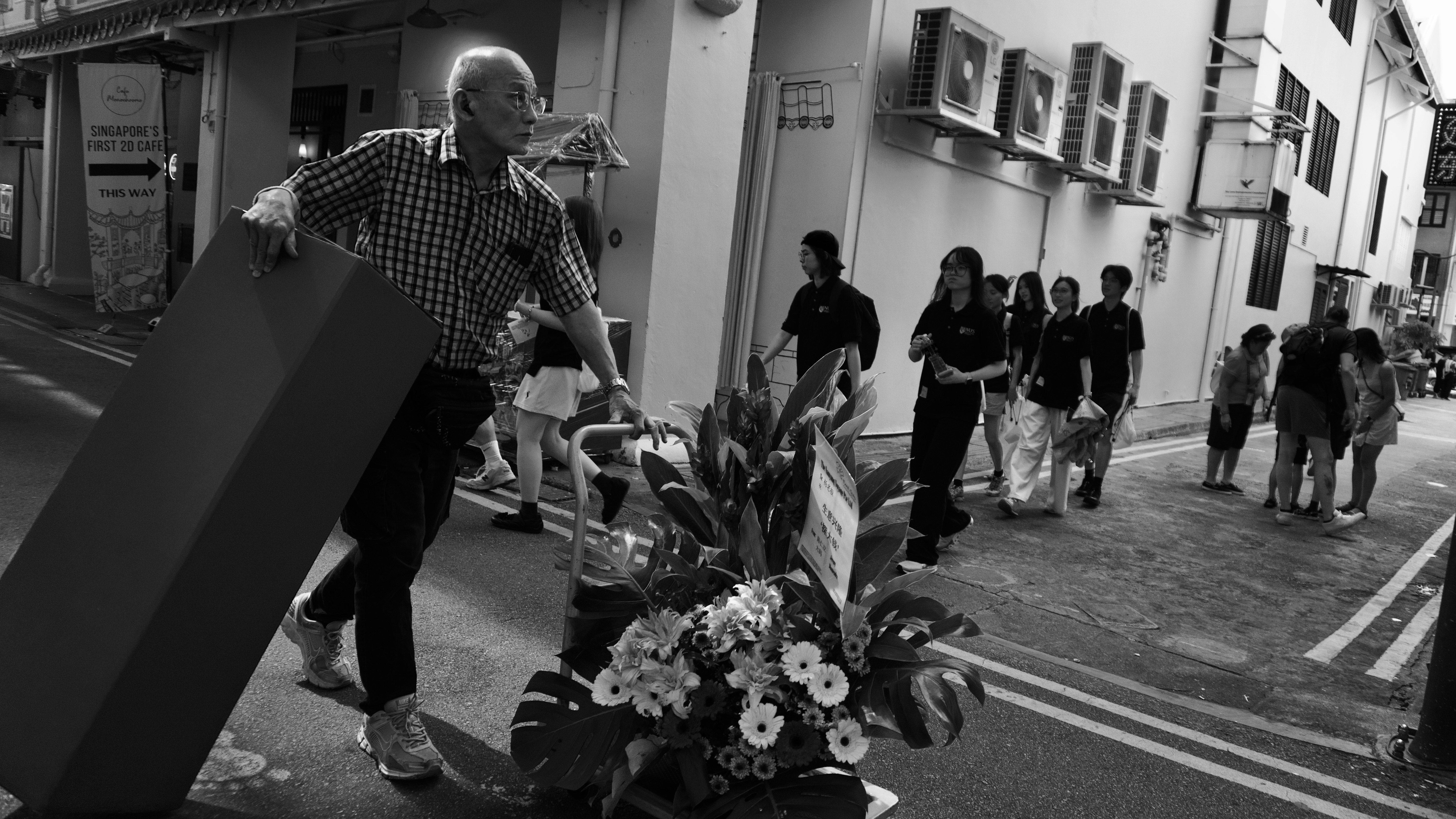 花束を運ぶ男性と路地の行列