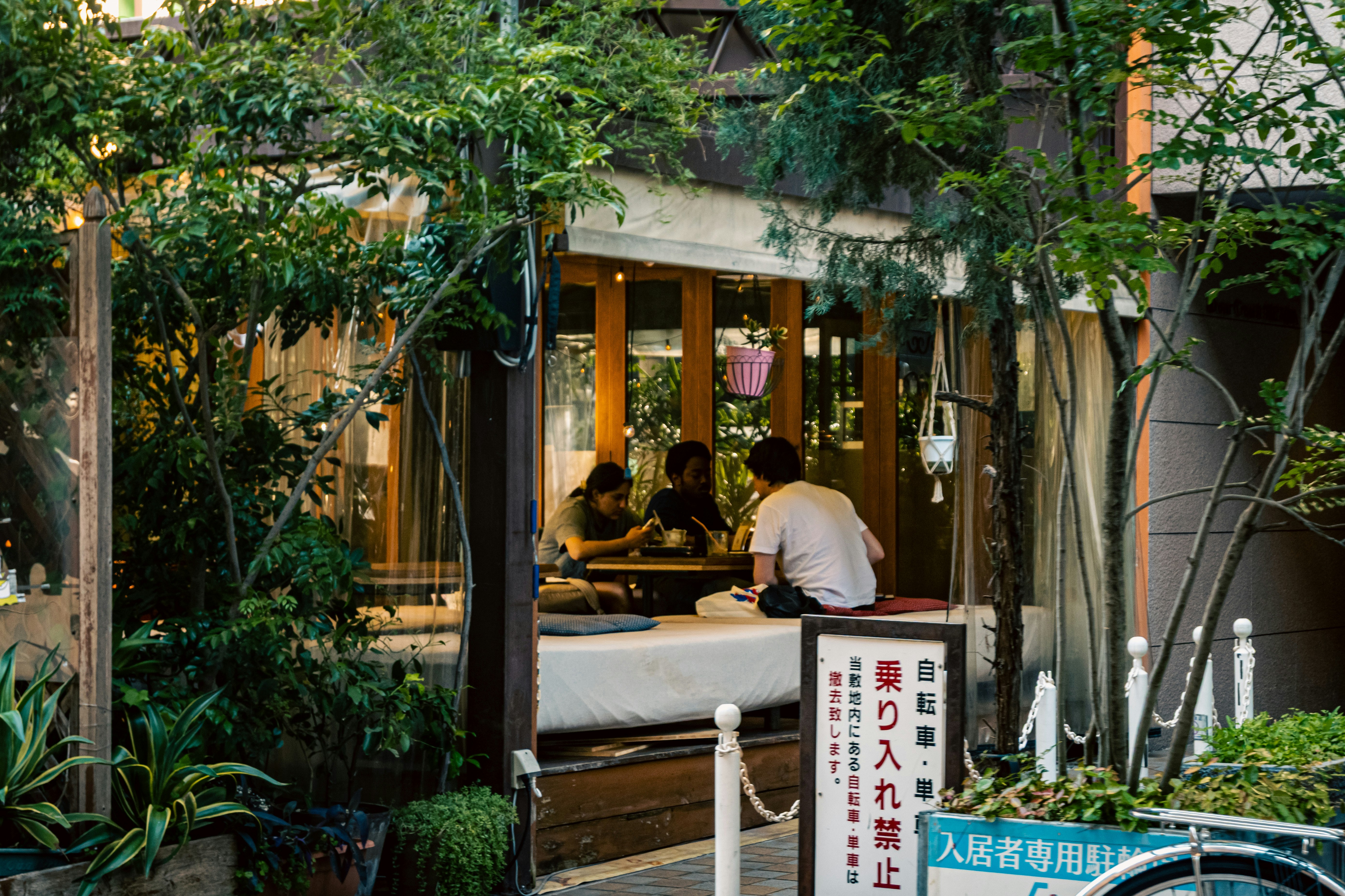 緑に囲まれた屋外のカフェ席と案内看板