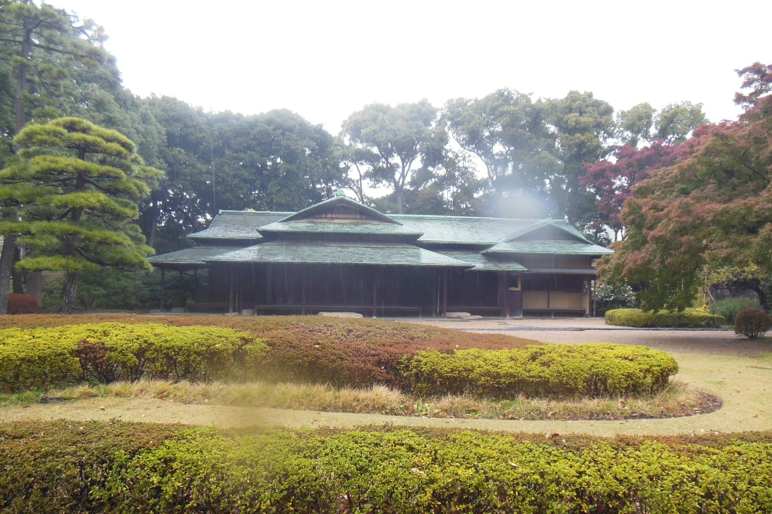 Traditionelles japanisches Haus mit grünem Dach umgeben von üppigem Grün