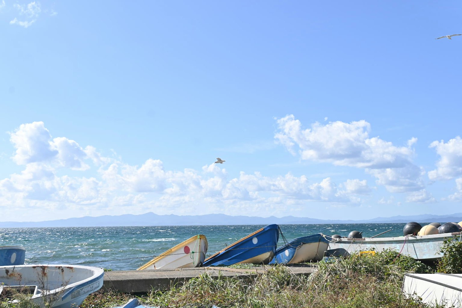 Pemandangan perahu kecil di pantai di bawah langit biru dengan awan