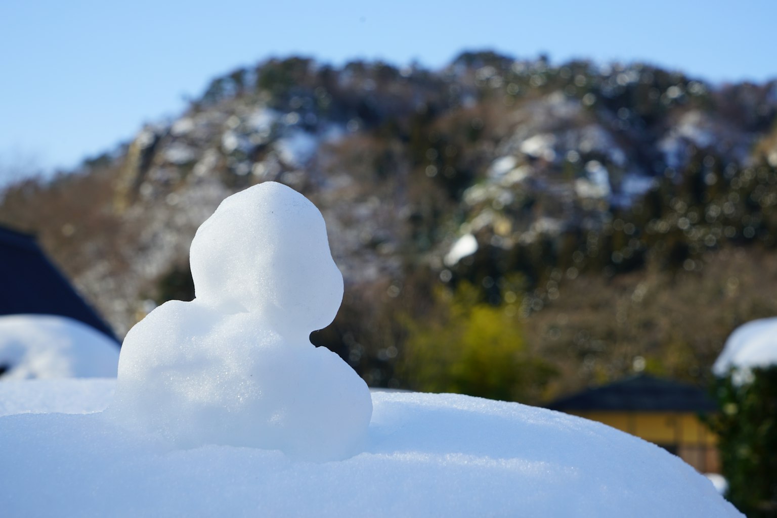 一个雪人形状的雪堆和背景中的山脉