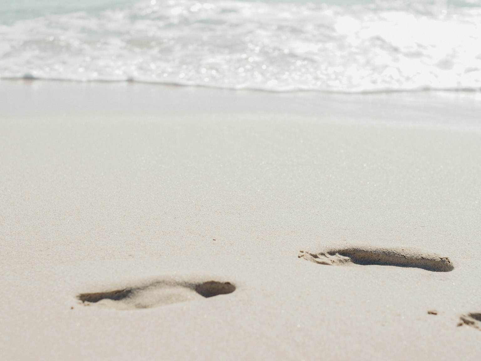 Empreintes sur une plage de sable avec des vagues