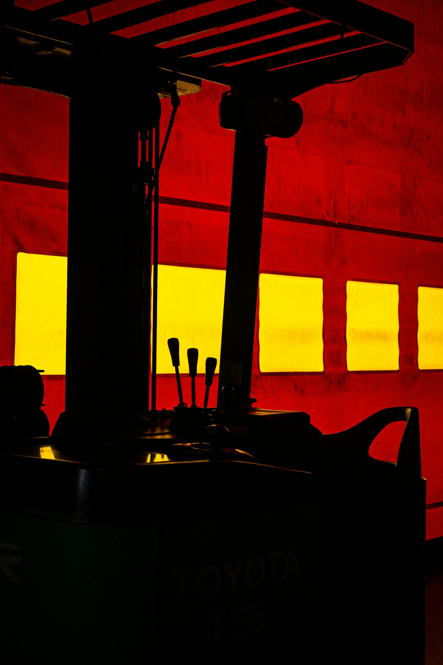 赤と黄色の背景にフォークリフトのシルエットが映る