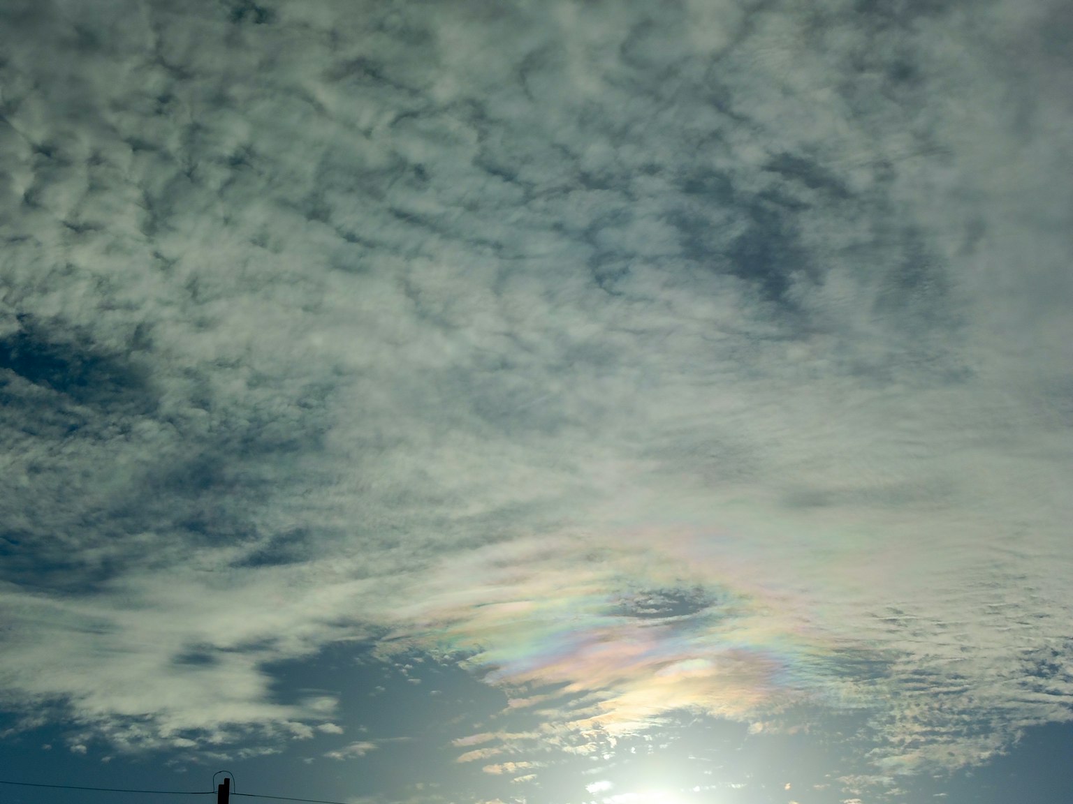 Cloudy sky with rainbow colors around the sun